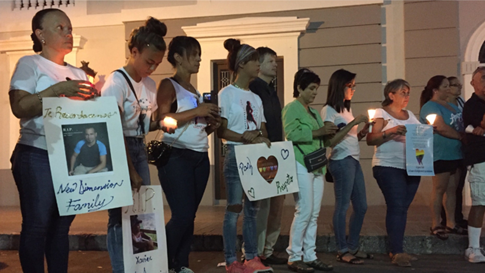 People gather with posters and candles in Ponce, Puerto Rico, Monday, June 13, 2016, during a vigil for the victims of Sunday's Orlando shootings at a gay nightclub in Florida. At least 5 of the 49 victims were from Ponce, the second largest city on Puerto Rico's southern coast. (AP Photo/Danica Coto)