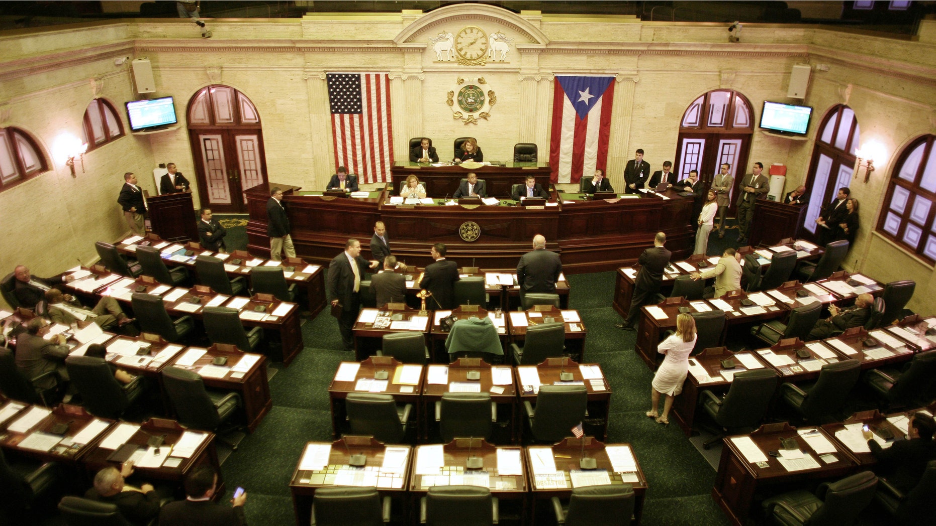In this photo taken on Thursday, Jan. 11, 2012, members of the house attend a session at the capitol in San Juan, Puerto Rico. A voter referendum will ask the people of the U.S. island territory if they want to amend their Constitution and fire dozens of members of their Senate and House of Representatives as a cost-savings measure, reducing the size of the legislature by almost 30 percent. The answer is almost certain to be a resounding yes. (AP Photo/Ricardo Arduengo)