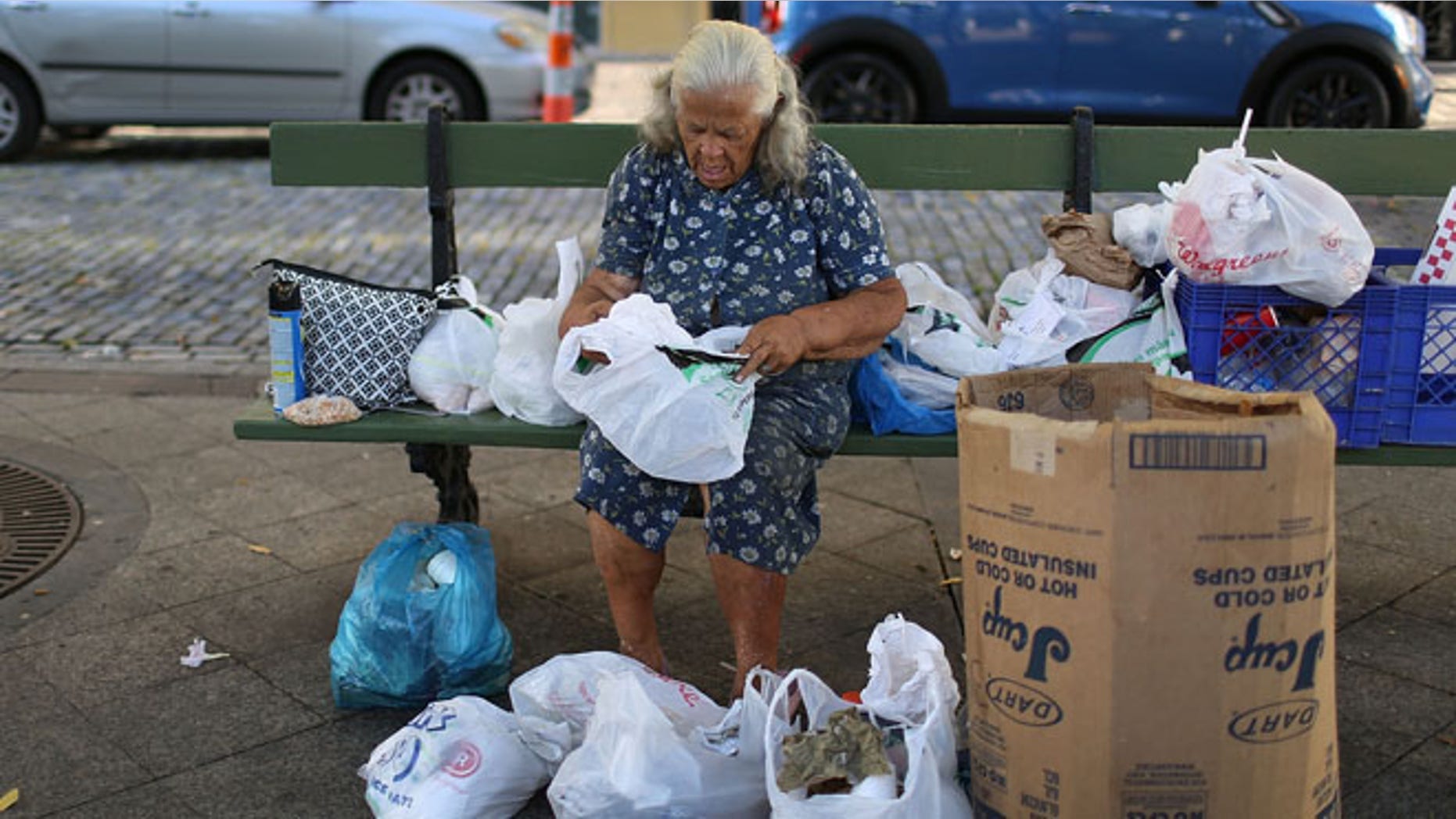SAN JUAN, PUERTO RICO - JUNE 30: A woman sorts through her belongings on a park bench a day after the speech Puerto Rican Governor Alejandro Garcia Padilla gave regarding the government's $72 billion debt on June 30, 2015 in San Juan, Puerto Rico. The Governor said in his speech that the people will have to sacrifice and share in the responsibilities for pulling the island out of debt. (Photo by Joe Raedle/Getty Images)