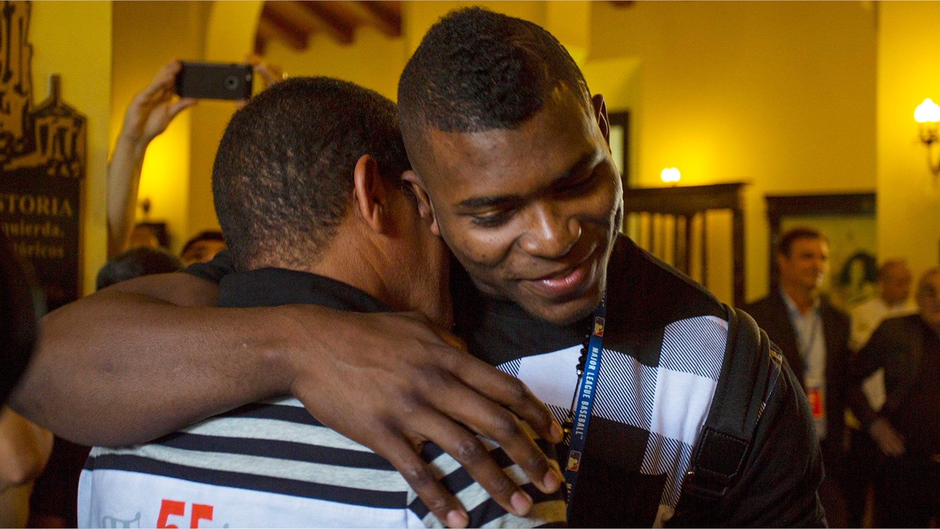 Los Angeles Dodgers outfielder Yasiel Puig, right, hugs his former coach Juan Arechavaleta as he arrives to Hotel Nacional in Havana, Cuba, Tuesday, Dec. 15, 2015. A lineup of Cuban baseball superstars including some of the most famous defectors in recent memory made a triumphant return Tuesday as part of the first Major League Baseball trip to the island since 1999. "I'm very happy to be here," said Puig, who had been barred from returning to Cuba until he was granted special permission for this week's trip. (AP Photo/Desmond Boylan)