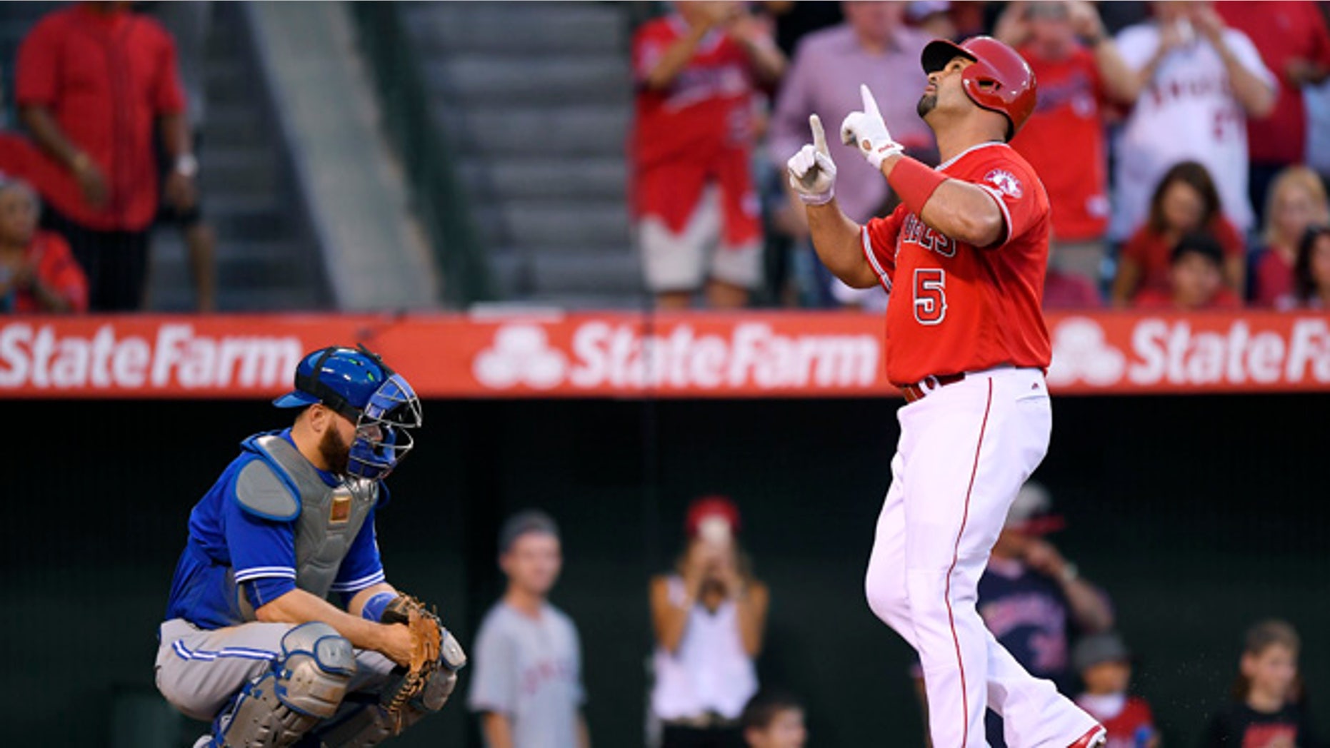 Los Angeles Angels' Albert Pujols, right, points to the sky as he scores after hitting a solo home run as Toronto Blue Jays catcher Russell Martin kneels at the plate during the second inning of a baseball game, Saturday, Sept. 17, 2016, in Anaheim, Calif. (AP Photo/Mark J. Terrill)