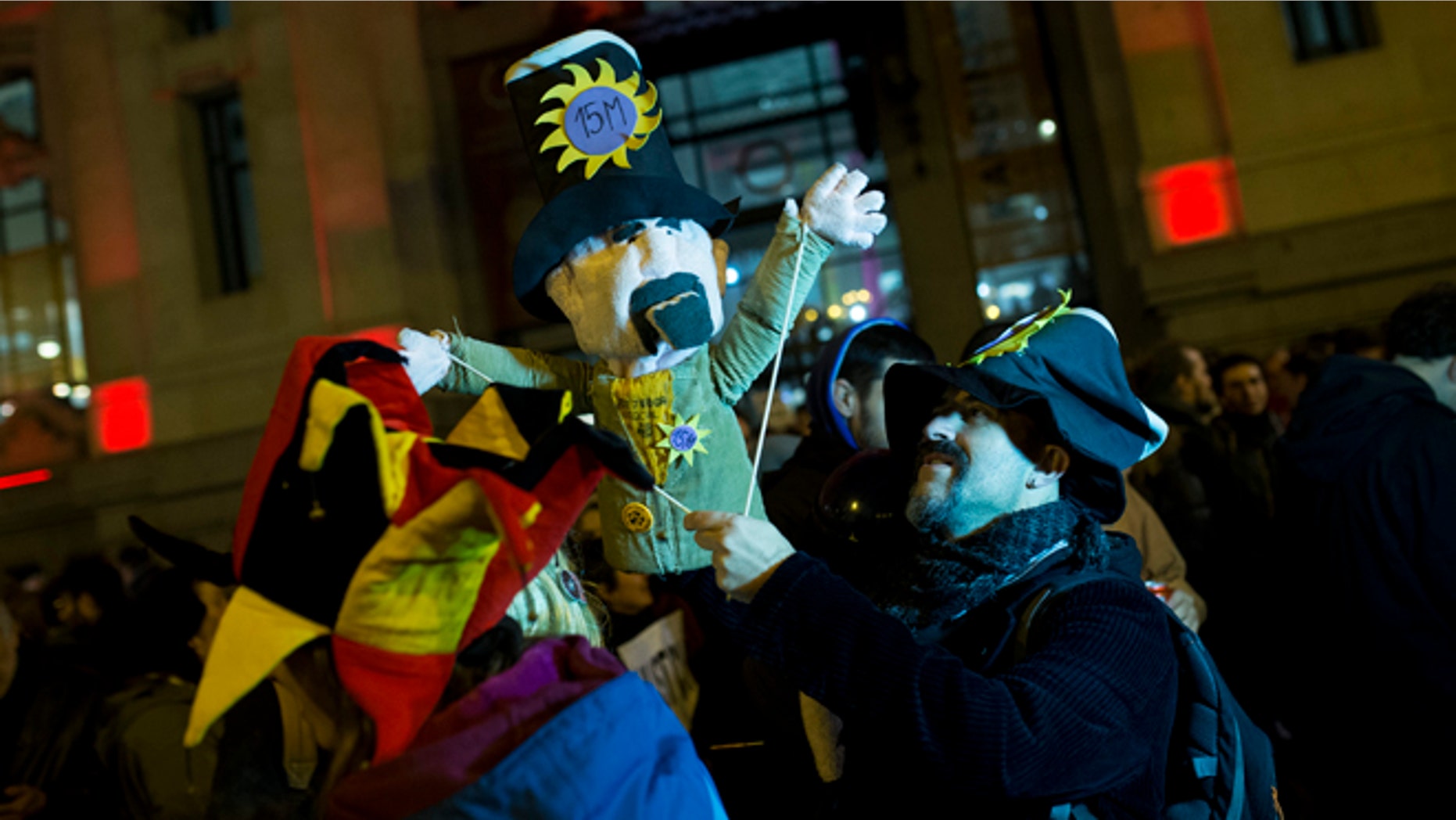A man, holding a puppet, gathers with others outside Madrid city hall in support of two puppeteers who were detained without a bail last Friday for using a sign saying, "Long Live Alka ETA," in a word-play reference to Spain's armed Basque group ETA and al-Qaida, in Madrid, Wednesday, Feb. 10, 2016. A Spanish court on Wednesday ordered the release of two puppeteers jailed since last week for allegedly praising terrorism in a controversial Carnival show funded with public money. (AP Photo/Francisco Seco)