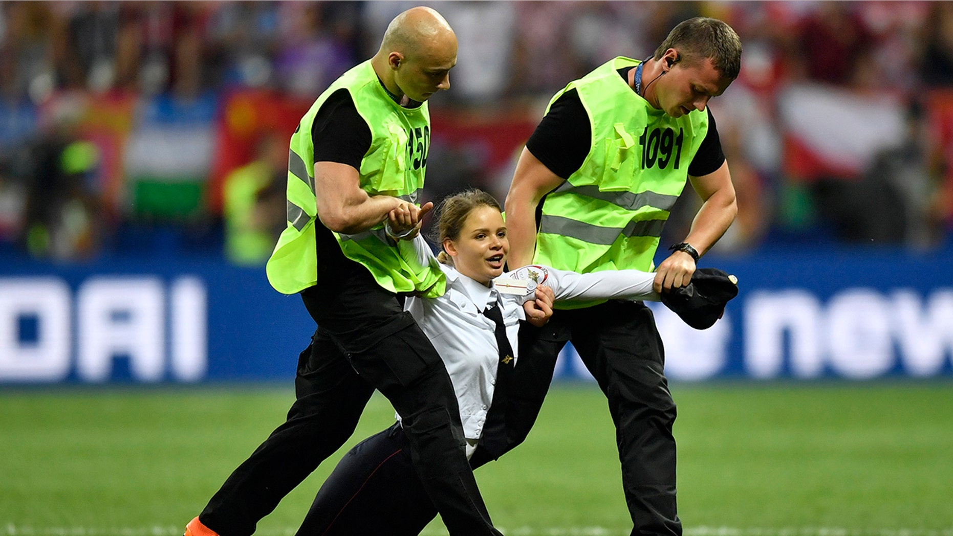 Stewards pull a woman off the pitch after she stormed onto the field and interrupted the final match between France and Croatia at the 2018 soccer World Cup in the Luzhniki Stadium.