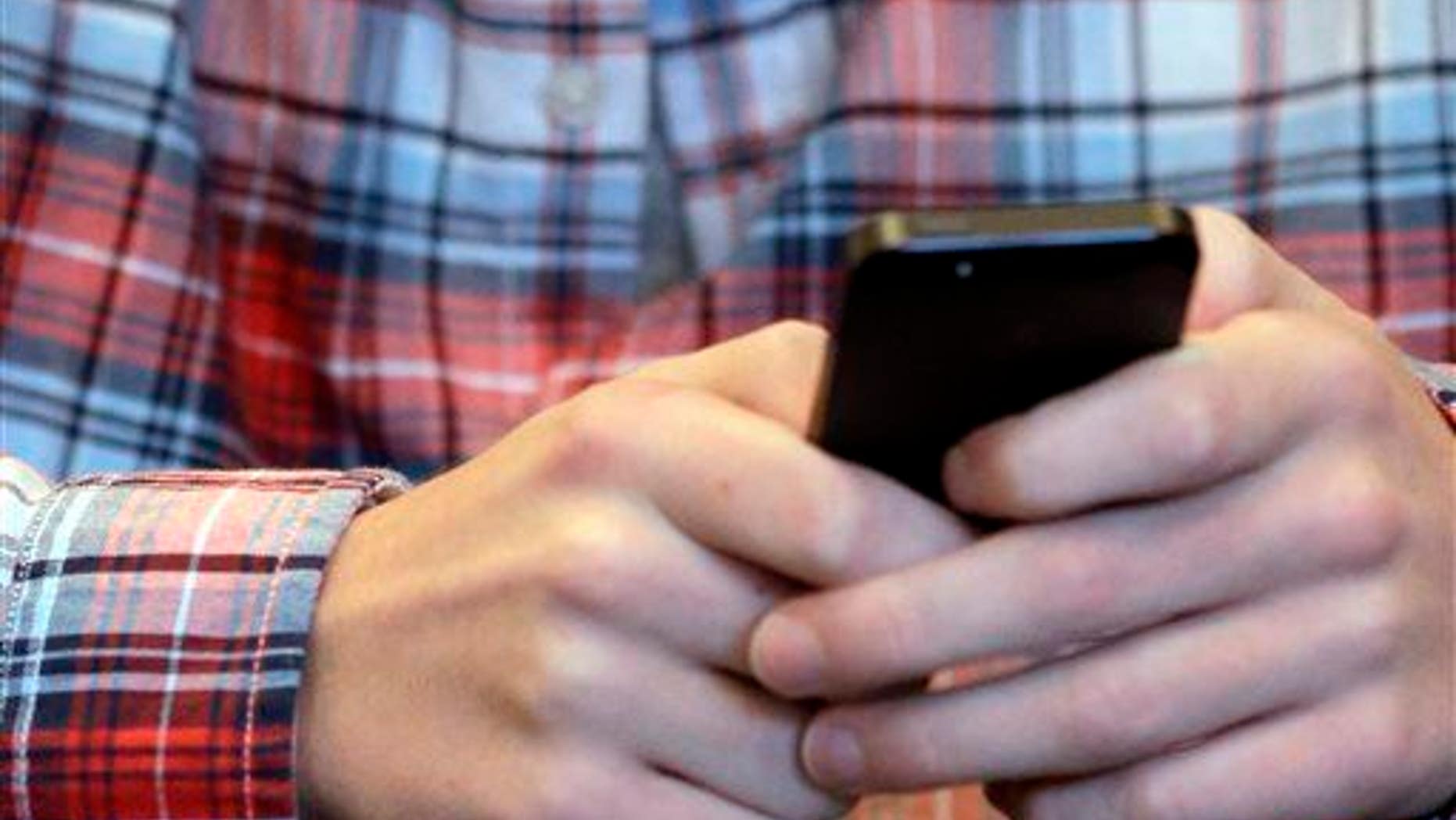 This Oct. 24, 2013, file photo shows someone checking his smartphone in Glenview, Ill.