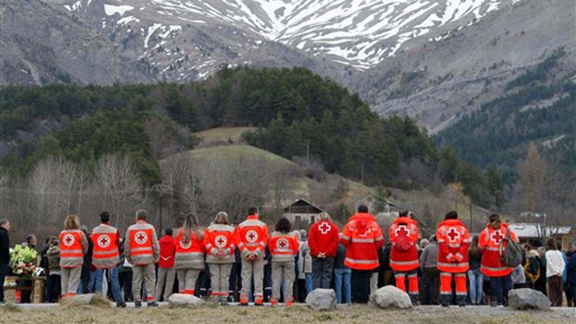 French Red Cross members pay tribute March 28, 2015, to the victims of a Germanwings plane crash in front of a stone slab erected as a monument in Le Vernet, France. (AP Photo/Claude Paris)