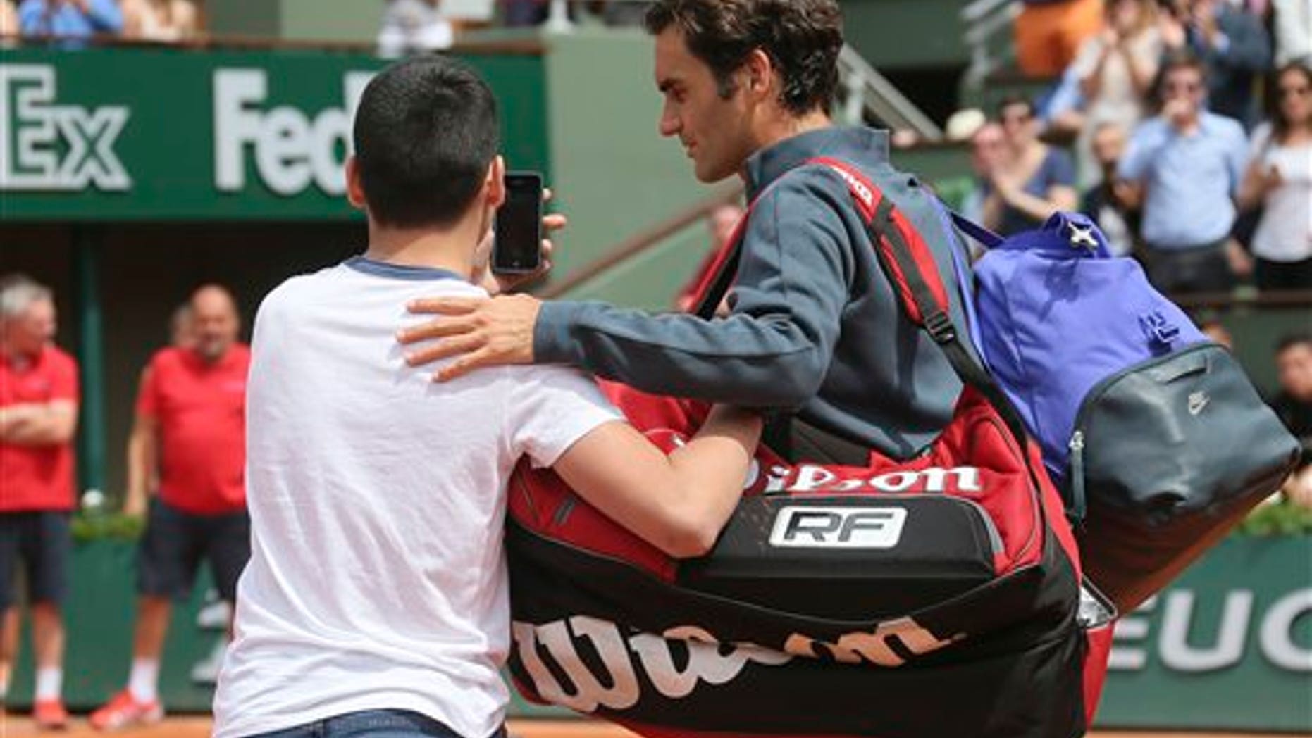 A boy who climbed down from the stands takes a selfie with Switzerland's Roger Federer in the first round match of the French Open tennis tournament in Paris, France, Sunday, May 24, 2015. (AP Photo/David Vincent)