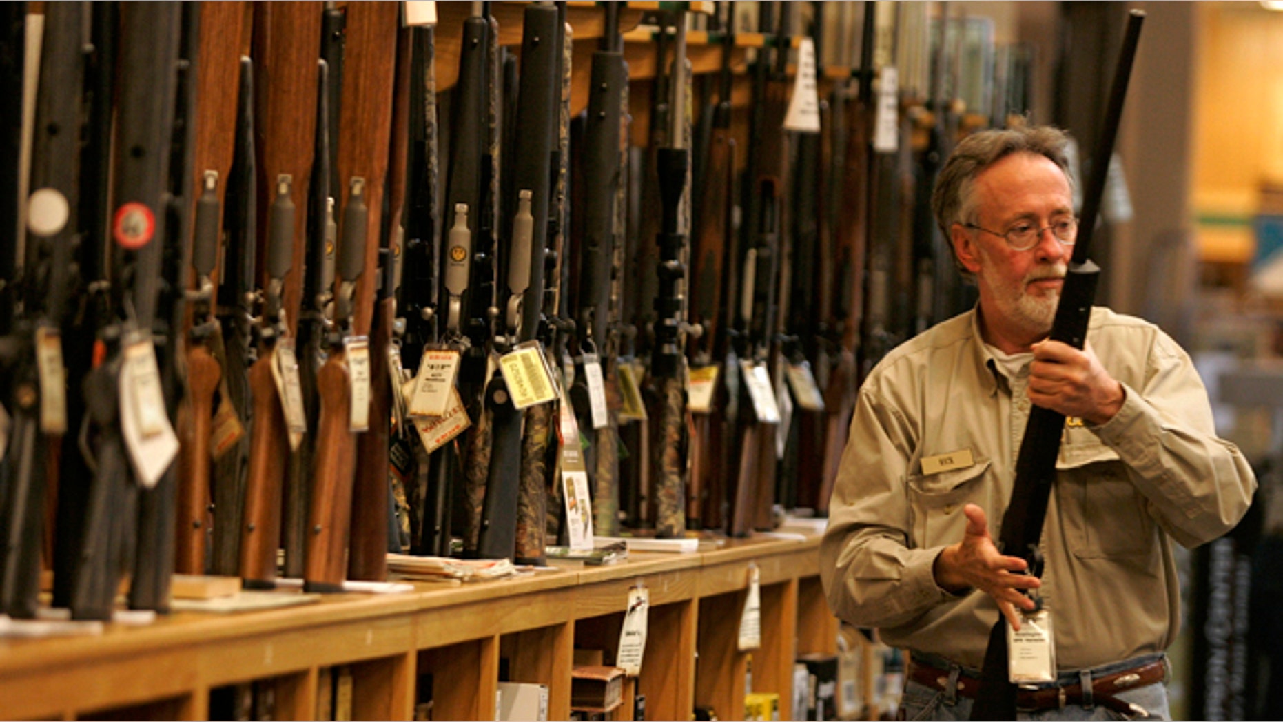 A salesman takes a rifle off the rack to show a customer at the Cabela's store in Fort Worth, Texas.
