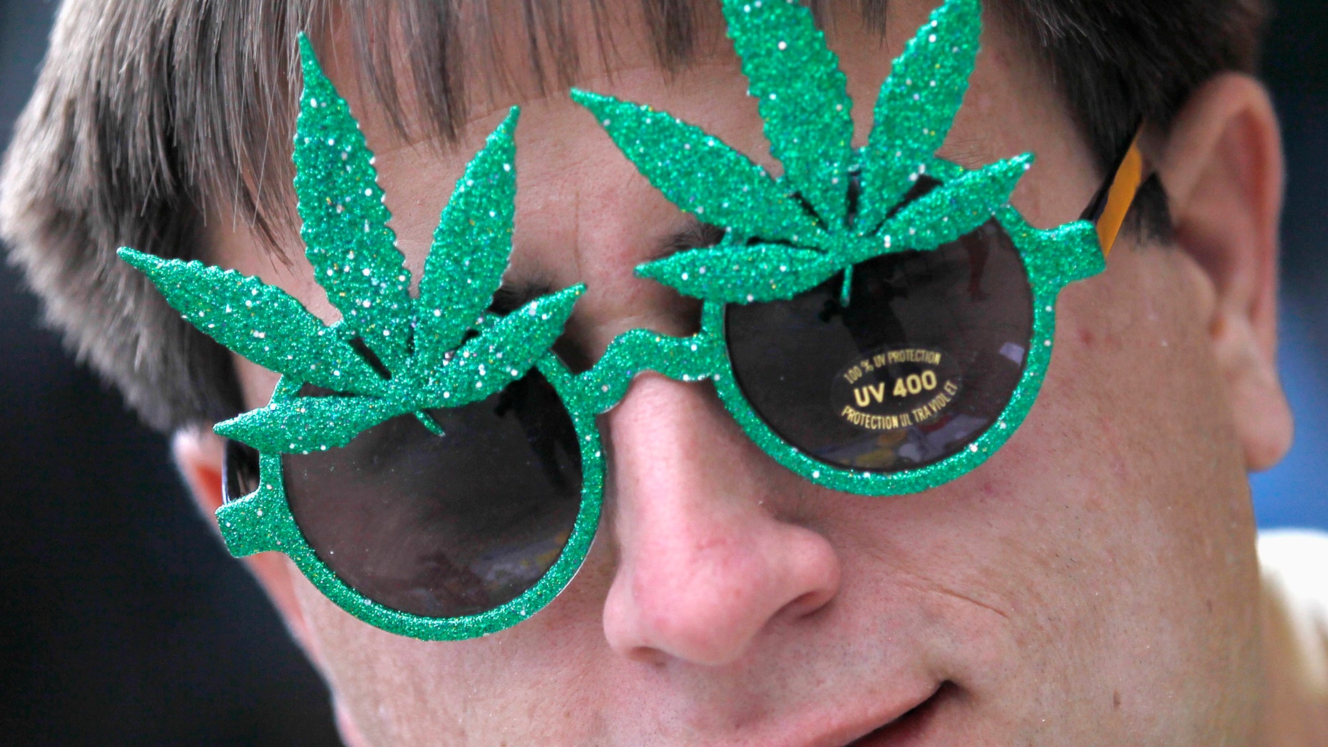 A man wears novelty sunglasses adorned with artificial marijuana leaves as he sells them across the street from a pro-marijuana rally at the University of Colorado in Boulder, Colorado April 20, 2012. (REUTERS/Rick Wilking)