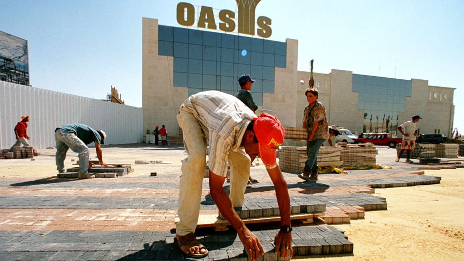 Palestinian laborers lay colored bricks in sand September 14, 1998 as they finish the entrance to the Oasis Casino.