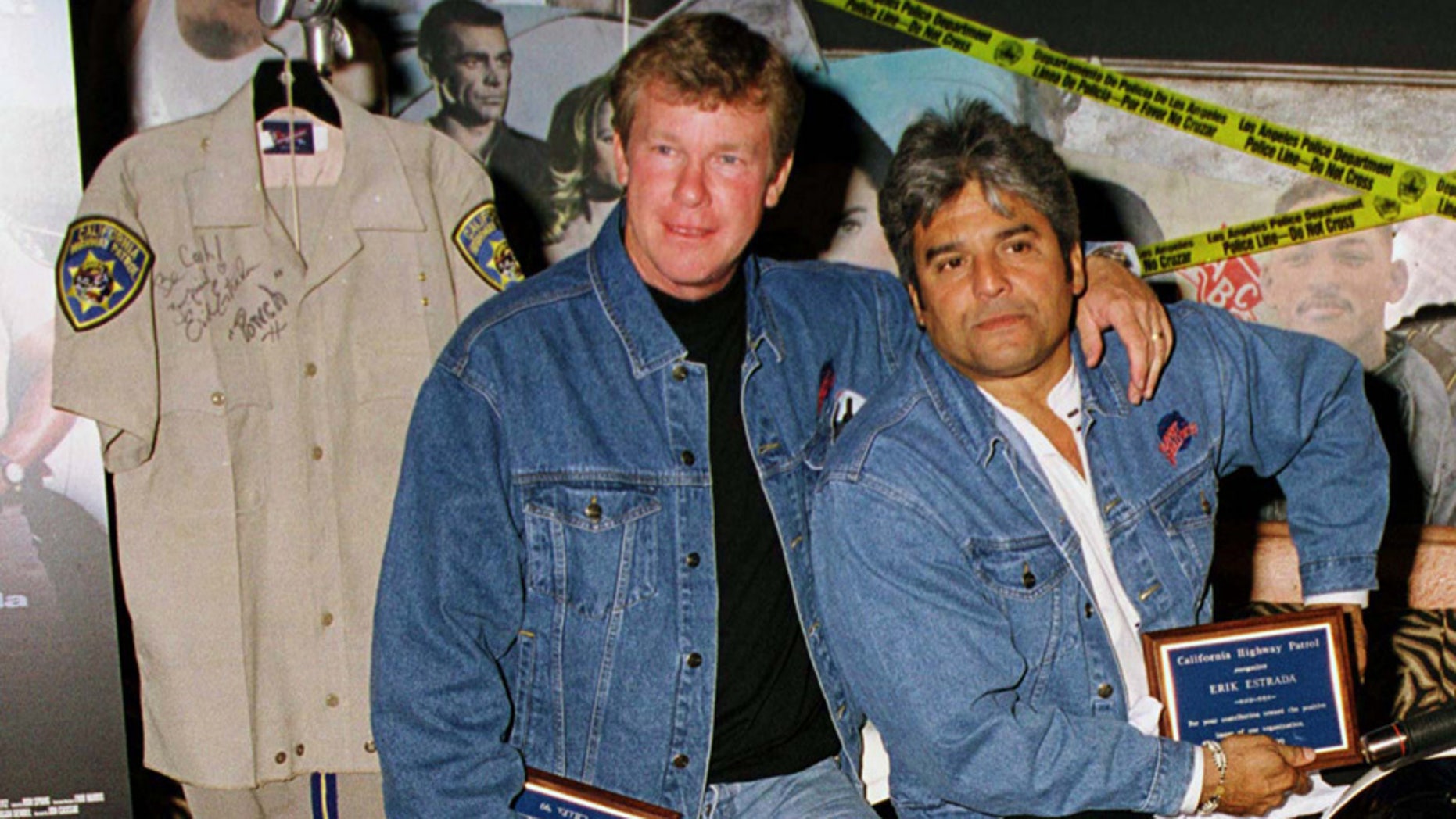 Actors Larry Wilcox (L) and Erik Estrada, stars of the original television series "CHiPs" pose with a uniform they donated to the memorabilia collection at Planet Hollywood Beverly Hills.