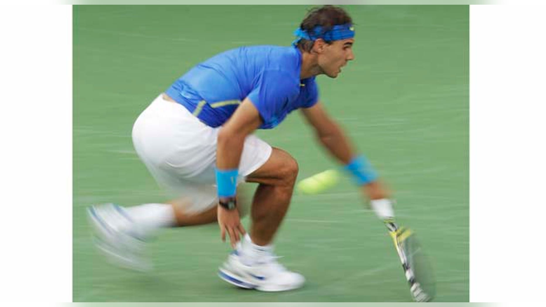 In a photo made using a slow shutter speed to create a blurred effect, Rafael Nadal of Spain returns a shot to Novak Djokovic of Serbia at the U.S. Open tennis tournament in New York, Monday, Sept. 12, 2011. (AP Photo/Charlie Riedel)