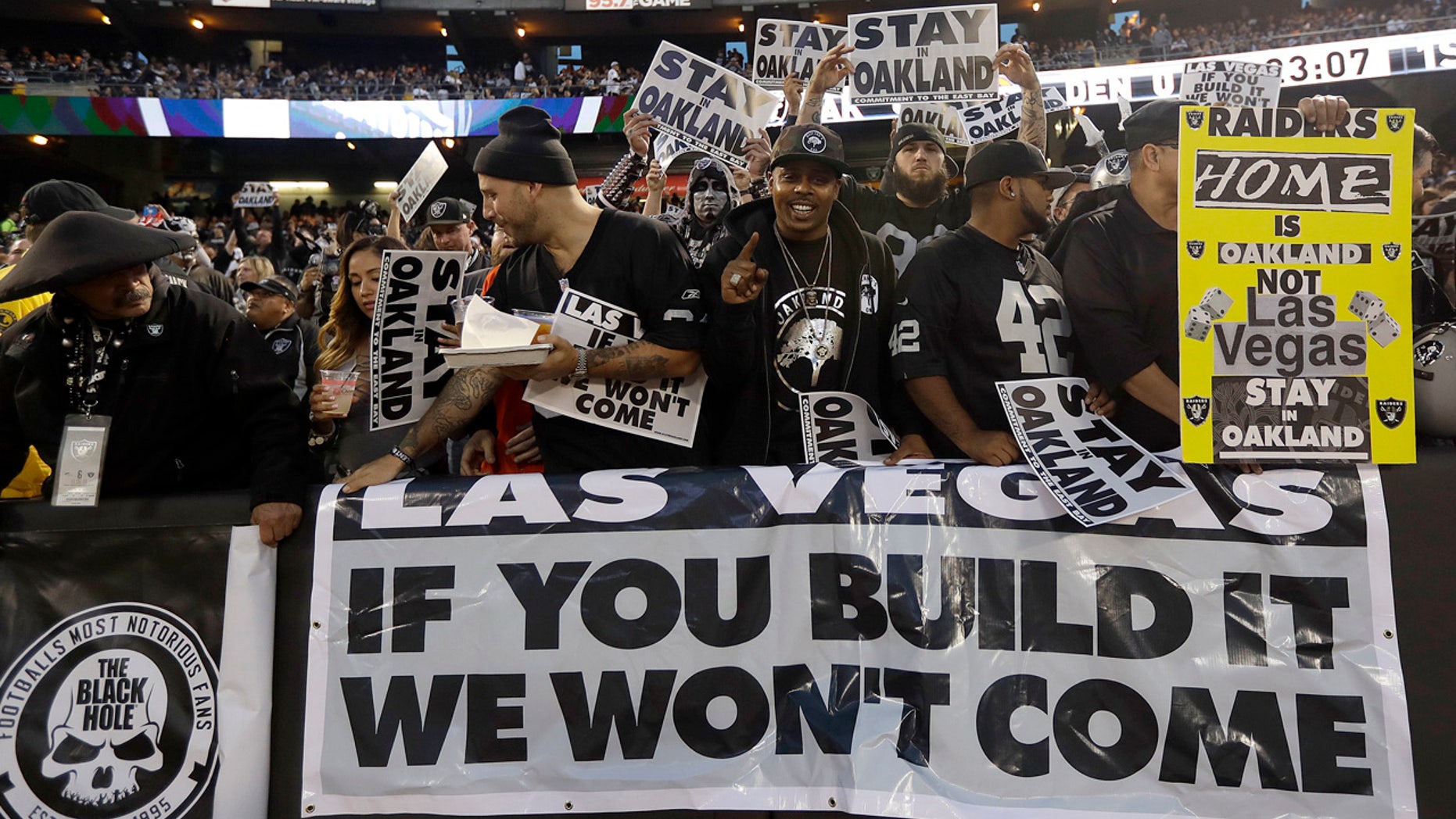 FILE - In this Nov. 6, 2016, file photo, Oakland Raiders fans hold up signs about the team's possible move to Las Vegas during an NFL football game between the Raiders and the Denver Broncos in Oakland, Calif.