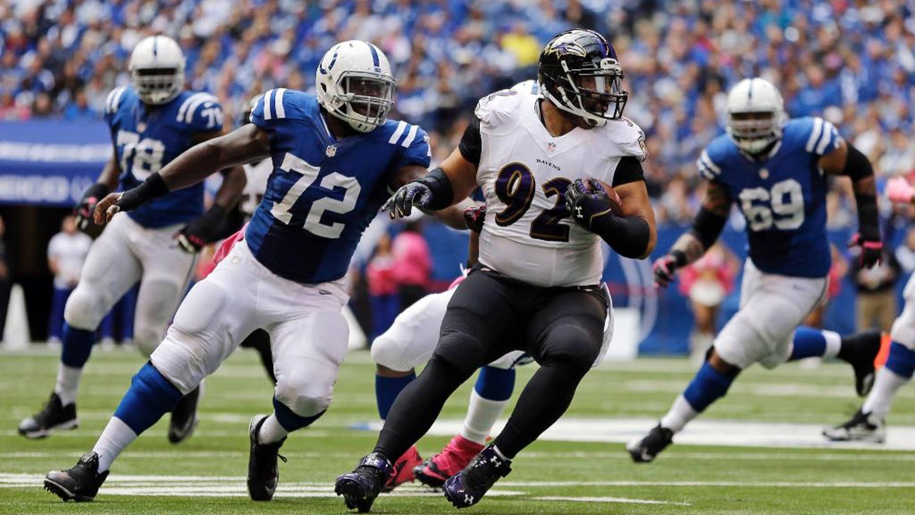 FILE - In this Oct. 5, 2014, file photo, Baltimore Ravens nose tackle Haloti Ngata (92) is chased by Indianapolis Colts center Jonotthan Harrison (72) after intercepting a pass during the first half of an NFL football game in Indianapolis. There is seemingly no limit to the ways in which Ngata can help the Ravens win. He stops the run, intercepts passes, has served as a blocking back and last Sunday took over as the long snapper for injured Morgan Cox. (AP Photo/Jeff Roberson, File)