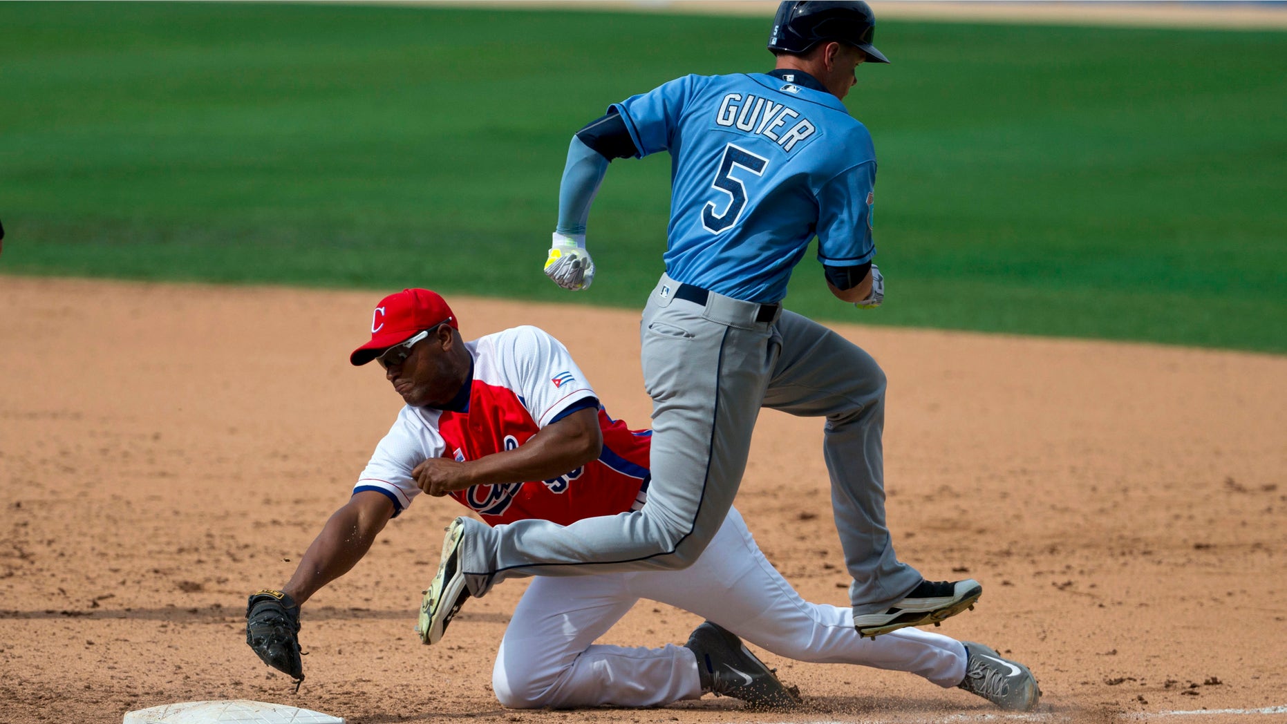 Cuba's Alexander Malleta dives for first base, too late to stop Tampa Bay Rays' Brandon Guyer during a game between the Rays and Cuba's national baseball team in Havana, Cuba, Tuesday, March 22, 2016. President Barack Obama and his family watched the game with Cuba's President Raul Castro, then left early for the airport where the first family departed for Argentina. Tampa Bay defeated Cuba 4-1. (AP Photo/Rebecca Blackwell)