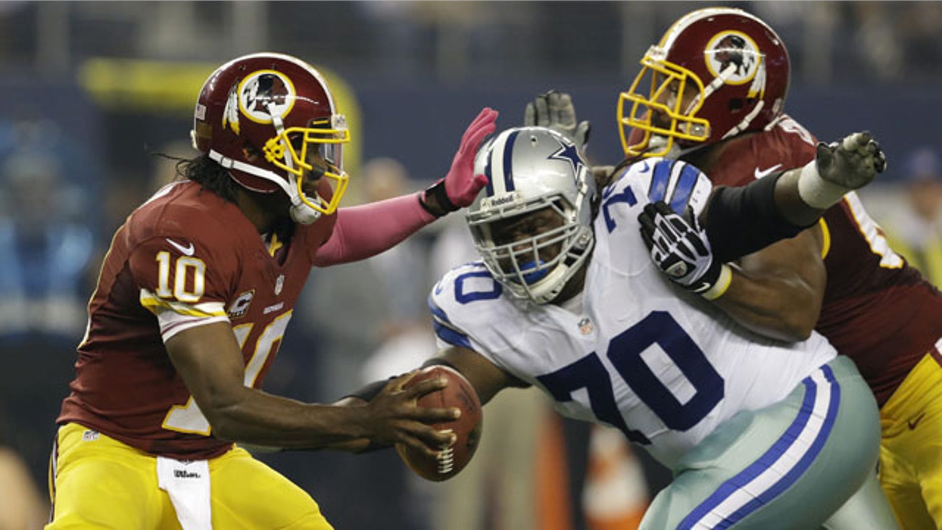 October 13, 2013: Washington Redskins quarterback Robert Griffin III (10) guards against a rush by Dallas Cowboys defensive tackle Drake Nevis (70) in the first half of an NFL football game Sunday in Arlington, Texas. (AP Photo/LM Otero)