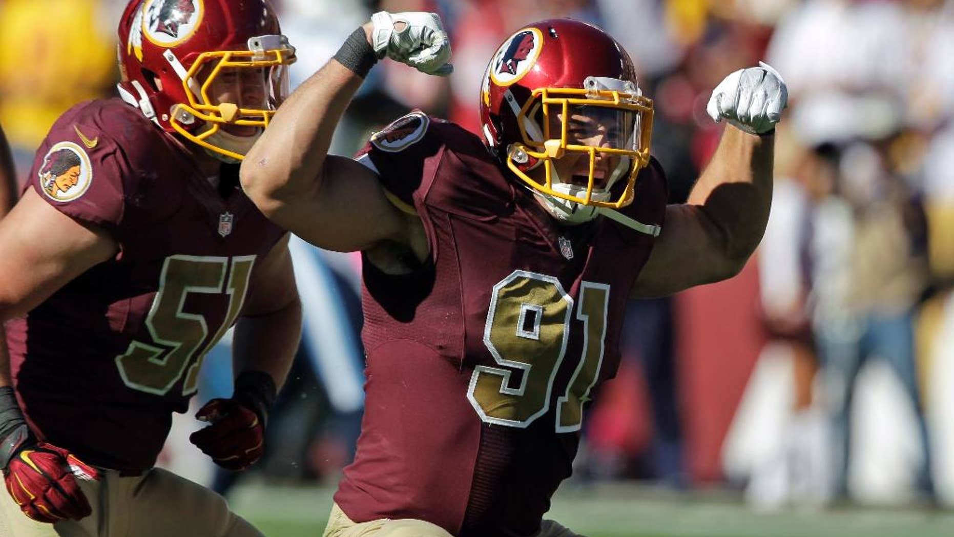 FILE - In this Oct. 19, 2014, file photo, Washington Redskins linebackers Ryan Kerrigan (91) and Will Compton (51) celebrate Kerrigan's sack during the second half of an NFL football game against the Tennessee Titans in Landover, Md. In contrast to, say, Robert Griffin III, Kerrigan is perhaps the most drama-free member of the Redskins. He leads the team with 7 and a half sacks, even though he's been playing hurt. (AP Photo/Mark E. Tenally, File)