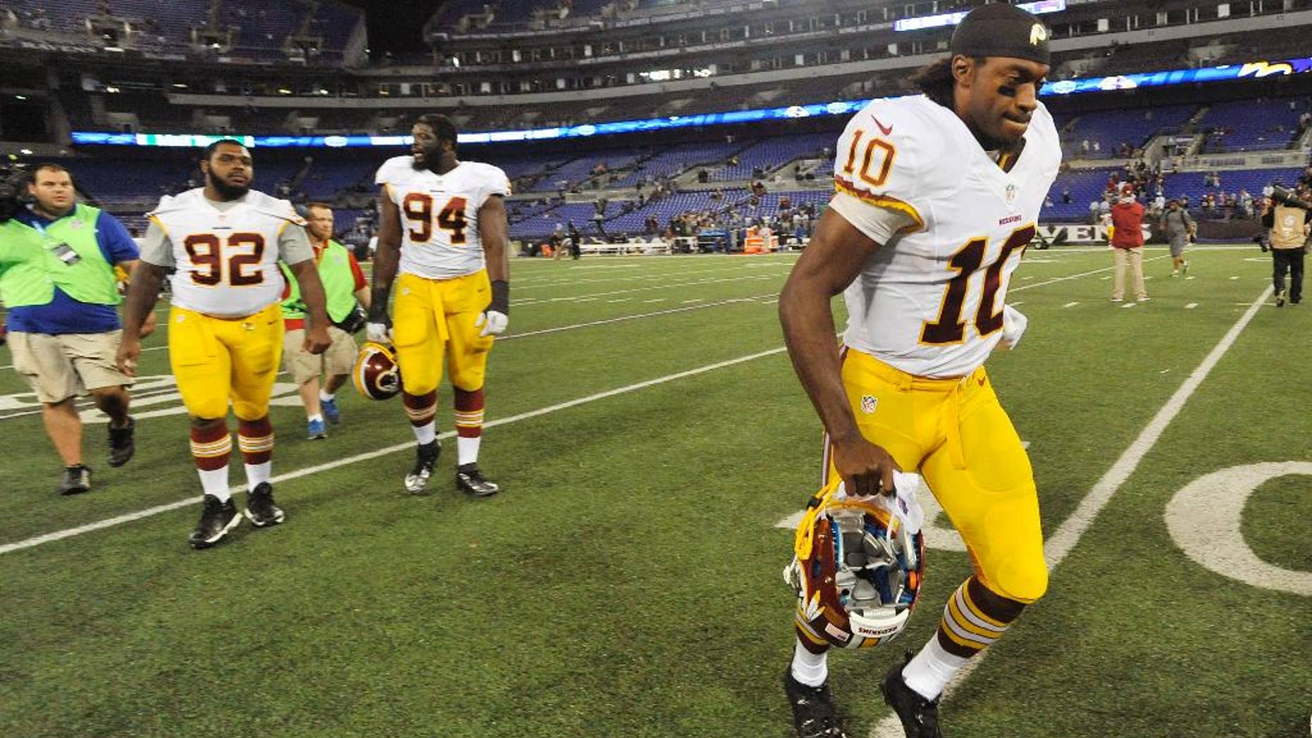 Washington Redskins quarterback Robert Griffin III, right, jogs off the field after an NFL preseason football game against the Baltimore Ravens, Saturday, Aug. 23, 2014, in Baltimore. Baltimore won 23-17. (AP Photo/Gail Burton)