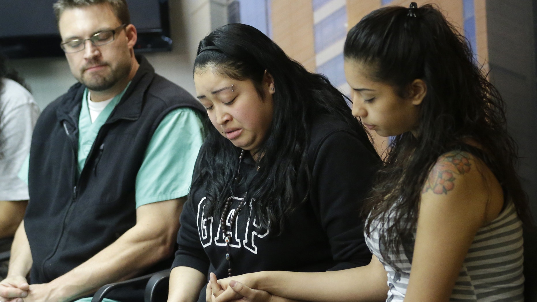 May 2, 2013: Johana Portillo, center, and her sister Ana Portillo hold hands while Dr. Shawn Smith looks on during a news conference at Intermountain Medical Center, in Murray, Utah. Ricardo Portillo, a Utah soccer referee, is in a coma after being punched by a teenage player unhappy with one of his calls, and his family says their only hope is for a miracle.