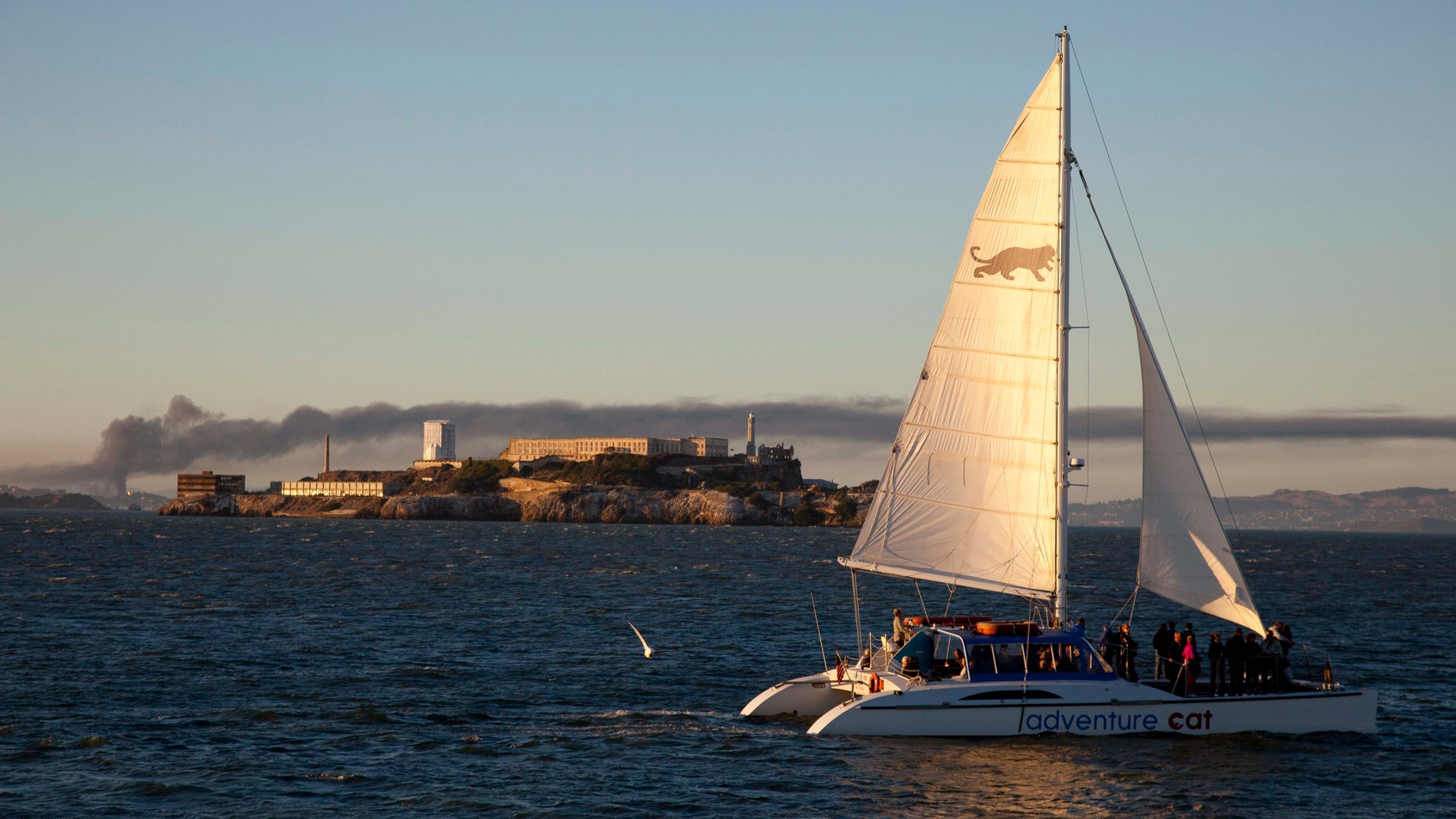 Aug. 6, 2012: Smoke pours from a fire at the Chevron Richmond Refinery, seen at left behind Alcatraz Island as a catamaran sails by in San Francisco.