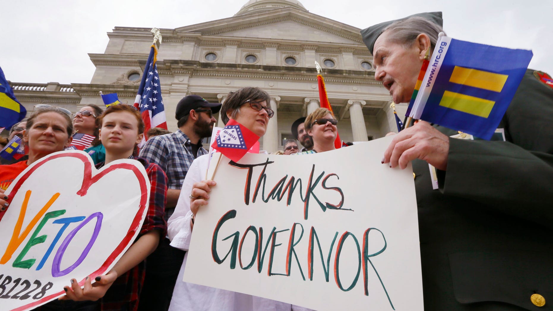 Kristen Hooper, center, and Robert Loyd, right, hold a sign on the steps of the Arkansas state Capitol thanking Arkansas Gov. Asa Hutchinson for calling for changes to a religious objection measure in Little Rock, Ark., Wednesday, April 1, 2015. The measure faced a backlash from businesses and gay rights groups. (AP Photo/Danny Johnston)