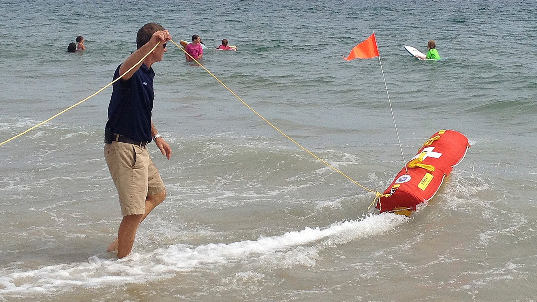 Aug, 8, 2012: Misquamicut, R.I., Fire Chief Louis Misto, left, holds a line attached to the EMILY remote-control lifesaving device as it propels itself in the water and away from the shore at Old Town Beach, in Westerly, R.I.