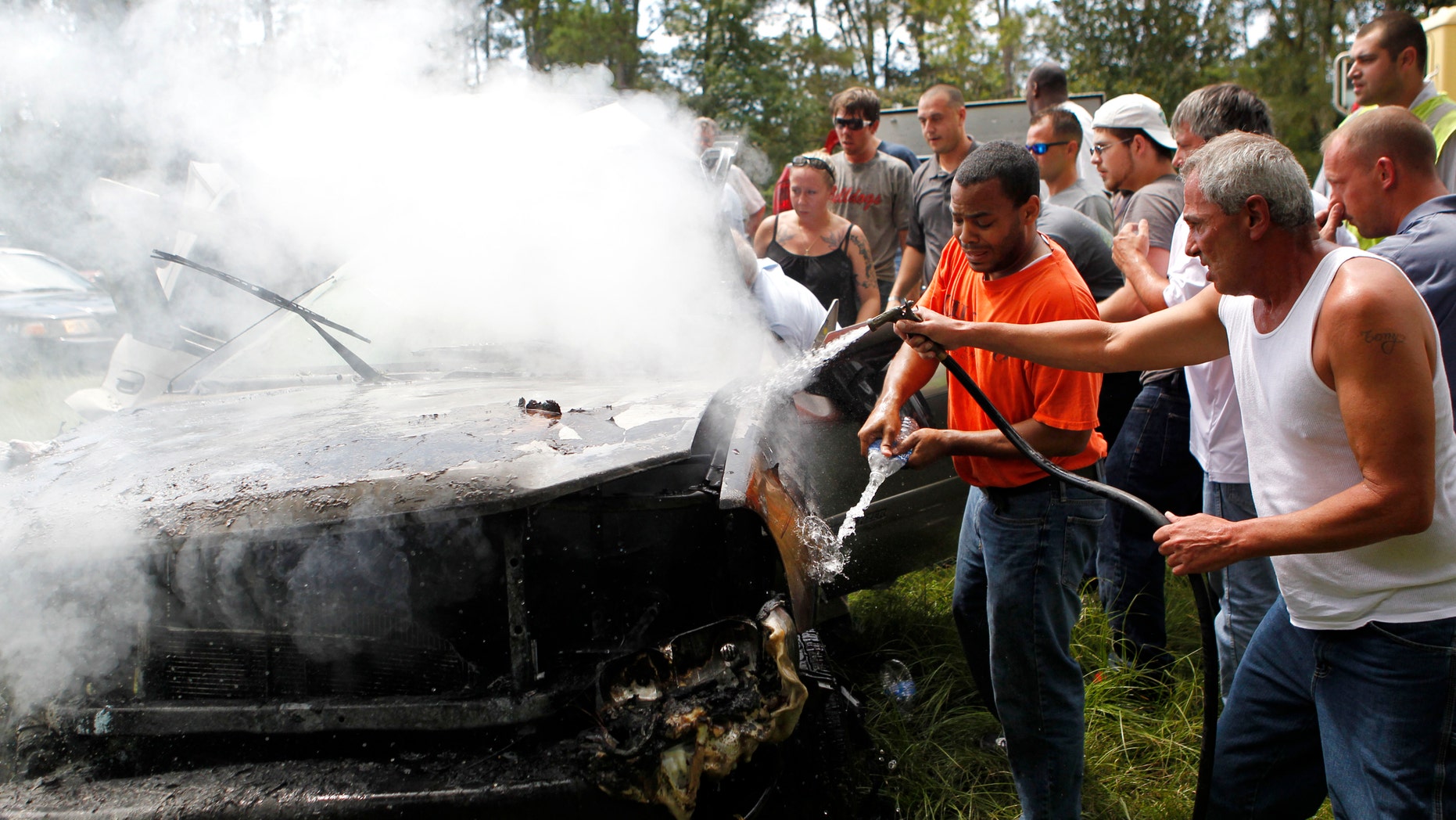 Aug. 16, 2012: Passers-by use a hose from a cement mixer and bottles of spring water to douse the fire as they rescue a woman pinned in a burning car on Interstate 10 in Hancock County, Miss.