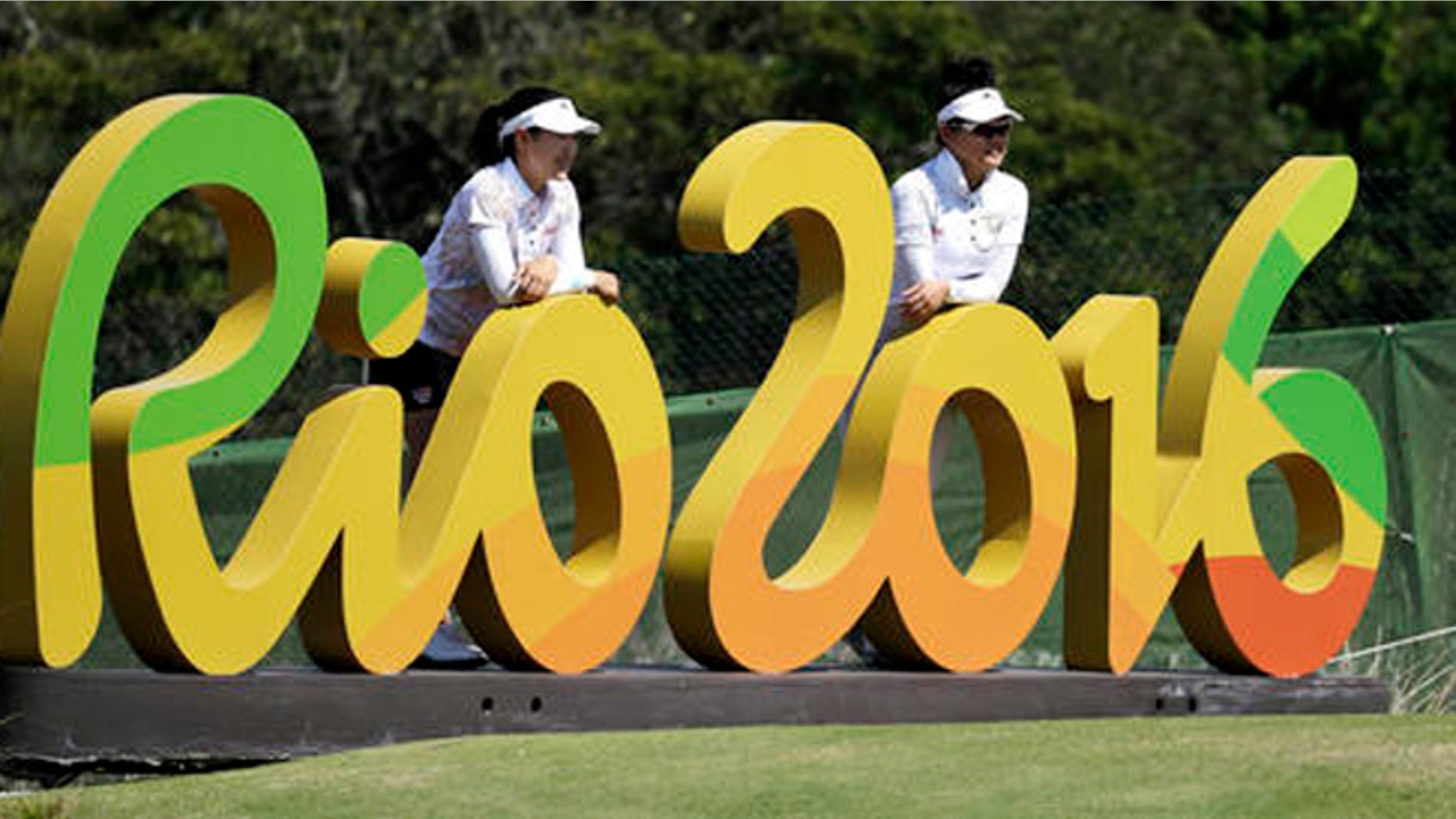 FILE - In this Aug.16, 2016 file photo, Kelly Tan, left, and Michelle Koh both of Malaysia, pose for a photo with the Rio 2016 logo on the 16th hole during a practice round for the women's golf event at the 2016 Summer Olympics in Rio de Janeiro, Brazil. The Rio Olympics could leave behind at least one unexpected legacy _ a new home for the consular office of the United States. The headquarters of the Rio de Janeiro Olympic organizing committee in central Rio will be abandoned in the next few weeks with staff moving to smaller quarters in downtown Rio. (AP Photo/Chris Carlson, File)
