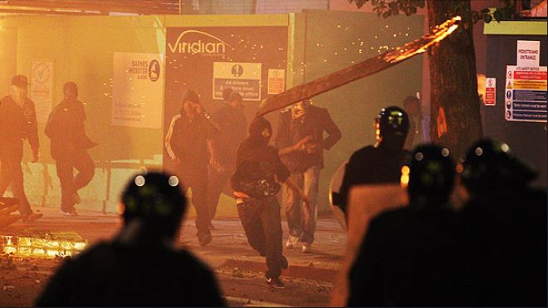Sun. 7: A rioter throws a burning wooden plank at police in Tottenham, north London, after members of a community, where a young man was shot dead by police, took to the streets to demand "justice."
