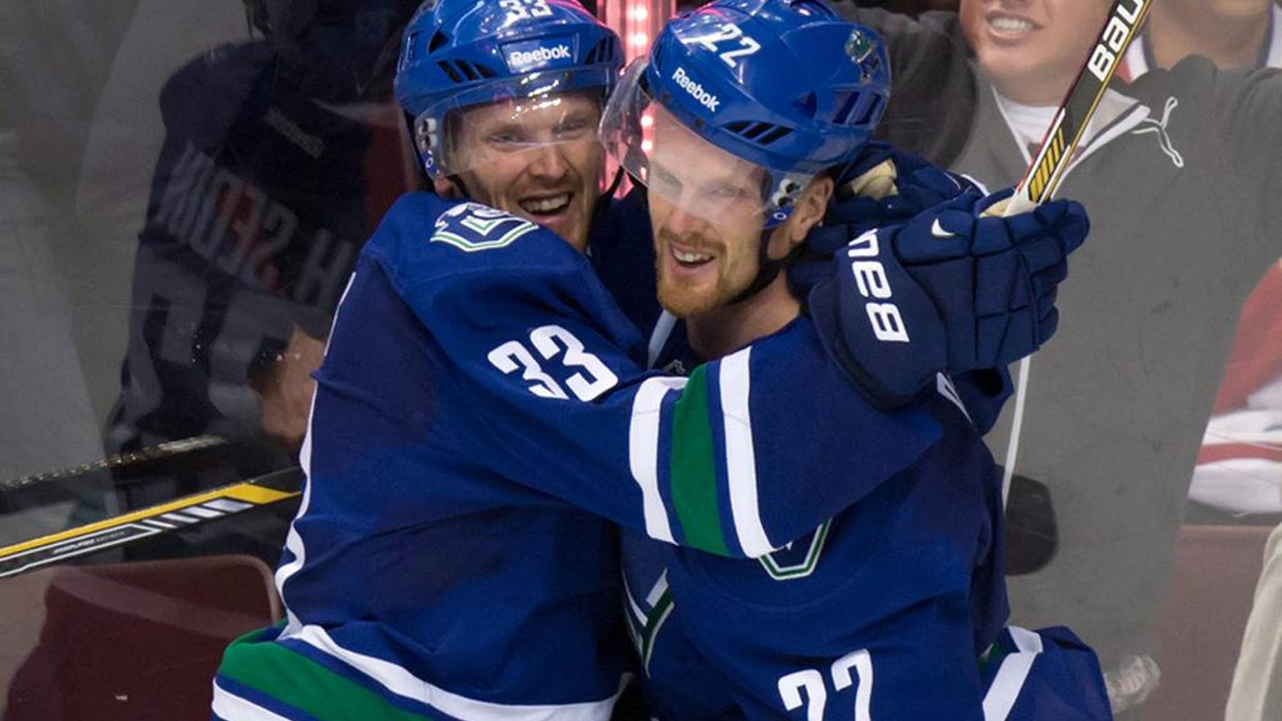 FILE - This Oct. 30, 2014, file photo shows Vancouver Canucks' Daniel Sedin, right, celebrating with his twin brother Henrik Sedin, both of Sweden, after scoring the winning goal against the Montreal Canadiens at an NHL hockey game in Vancouver. After the Canucks missed the playoffs last spring, they overhauled their front office and stripped their roster to its foundation, the Sedin twins. Many expected a lengthy rebuild but the revamped Canucks are off to a sizzling start in the Pacific Division. (AP Photo/The Canadian Press, Darryl Dyck,File)