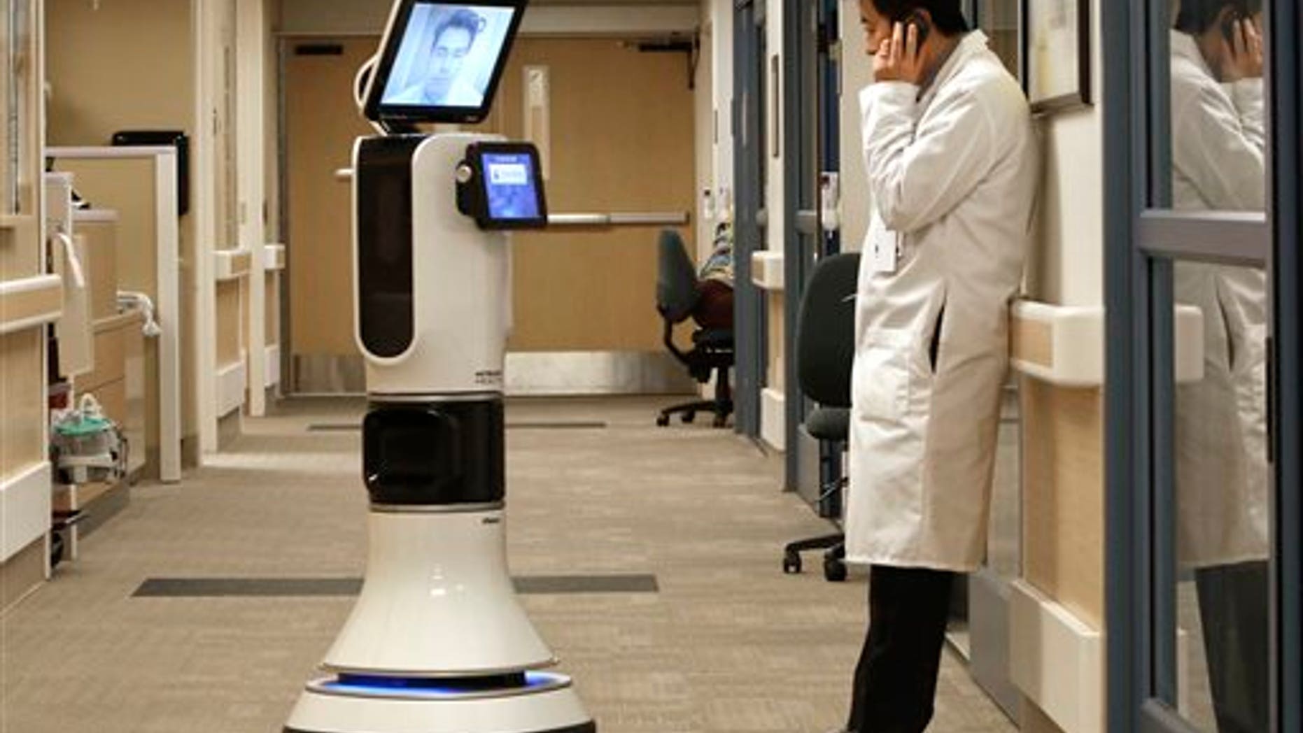 In this photo taken Wednesday, Nov. 6, 2013 Dr. Alan Shatzel, medical director of the Mercy Telehealth Network, is displayed on the monitor RP-VITA robot as he waits to confer with Dr. Alex Nee at Mercy San Juan Hospital in Carmichael, Calif. The robots enable physicians to have "beam" themselves into hospitals to diagnose patients and offer medical advice during emergencies. (AP Photo/Rich Pedroncelli)