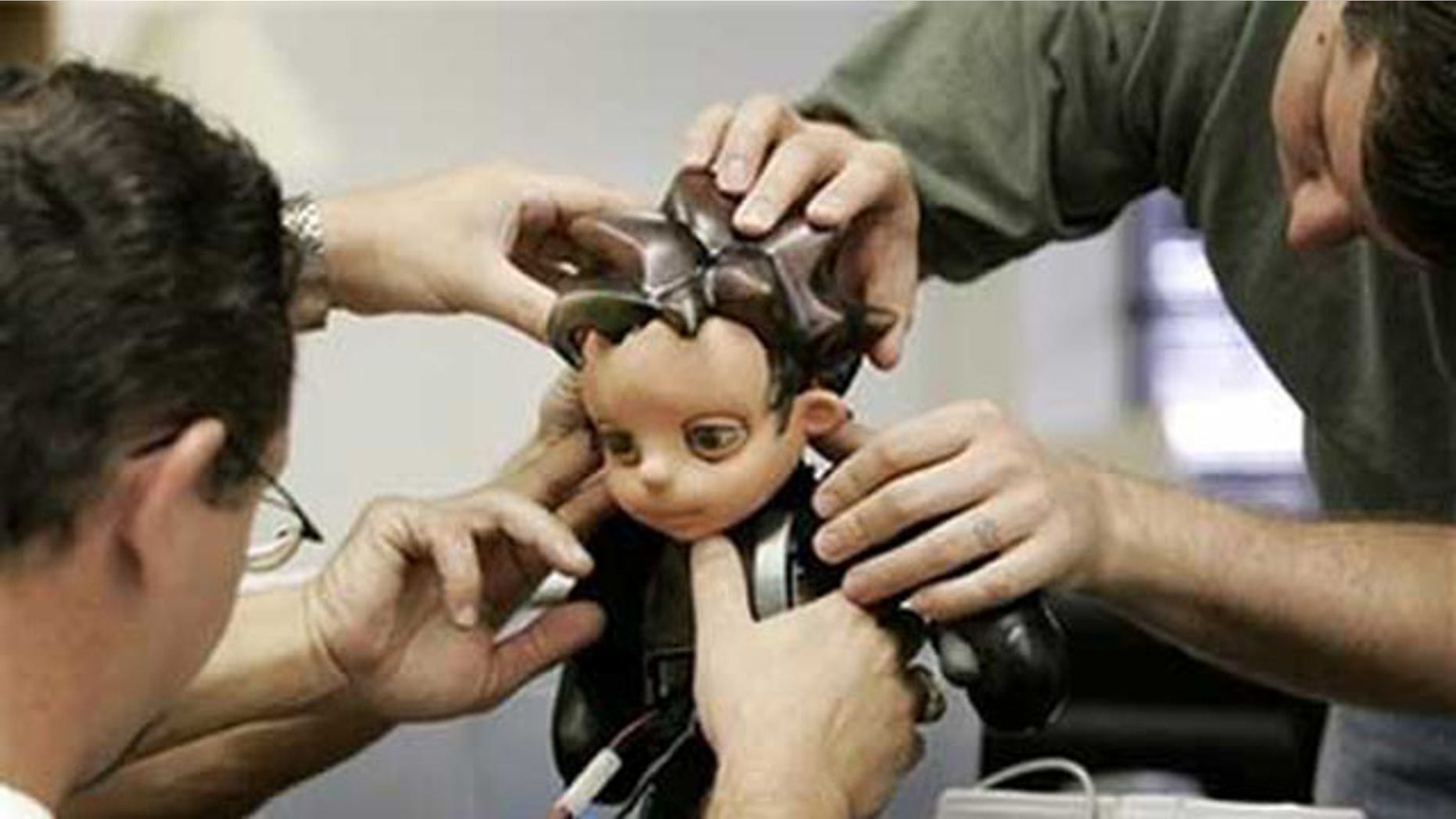 Jason Mitchell, left, and Joshua Varner, right, make adjustments to Zeno, a robot boy creation by Hanson Robotics. Japanese researchers hope a similar robot will help boost sagging birth rates.