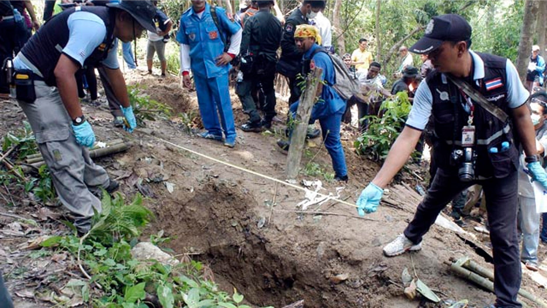 May 2, 2015: Thai police officials measure a shallow grave in Padang Besar, Songkhla province, southern Thailand. (AP Photo/Sumeth Panpetch, File)