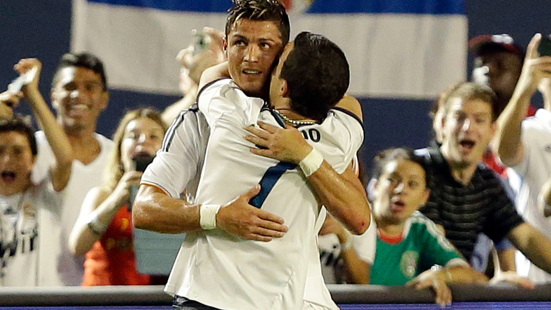 A man who ran onto the pitch hugs Real Madrid forward Cristiano Ronaldo, rear, during the second half of the International Champions Cup final soccer game between Real Madrid and Chelsea, Wednesday, Aug. 7, 2013, in Miami Gardens, Fla. (AP Photo/Wilfredo Lee)