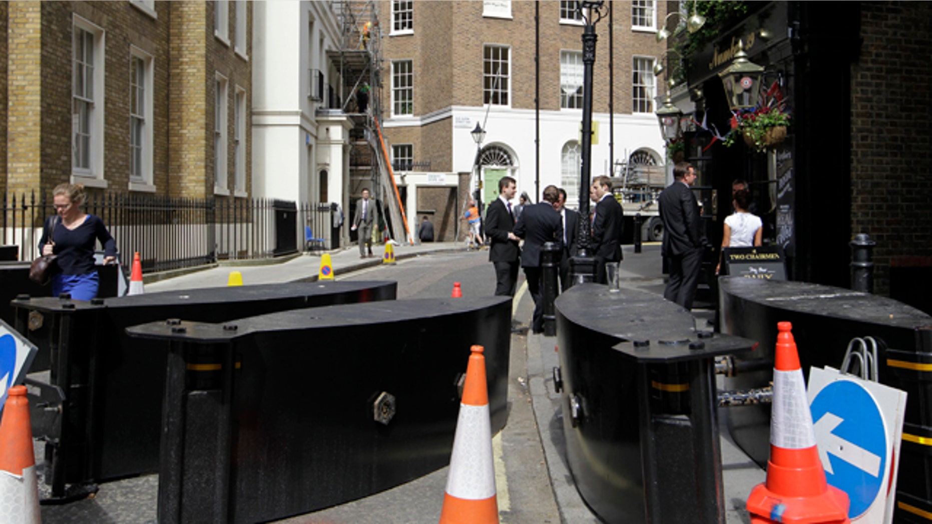 April 27, 2011: People mingle outside a pub on a street blocked off by security barriers near the Westminster Abbey in London in readiness for the royal wedding.