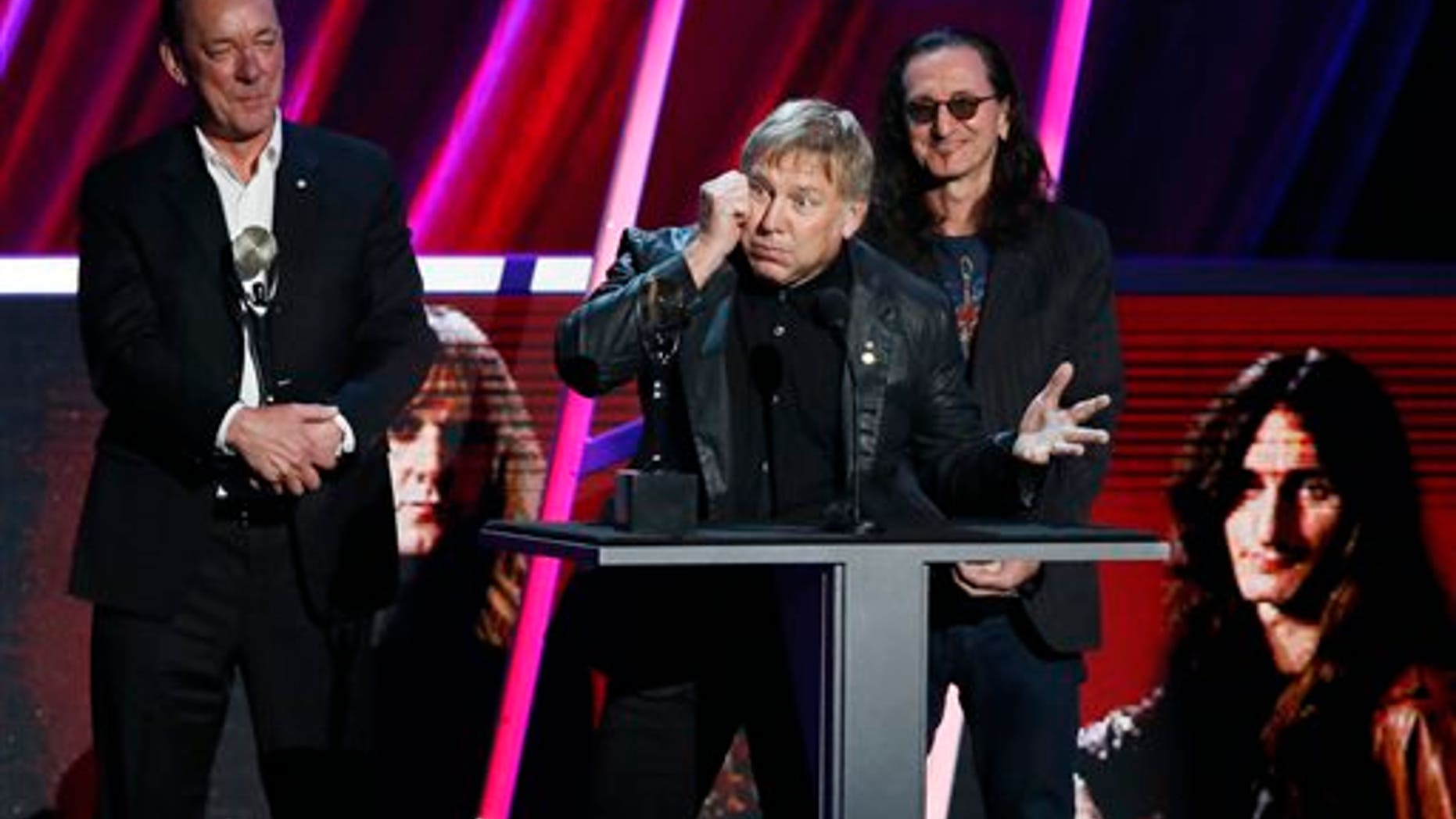 Alex Lifeson, center, Neil Peart, left, and Geddy Lee, right, of Rush accept their band's induction into the Rock and Roll Hall of Fame during the Rock and Roll Hall of Fame Induction Ceremony at the Nokia Theatre on Thursday, April 18, 2013 in Los Angeles.