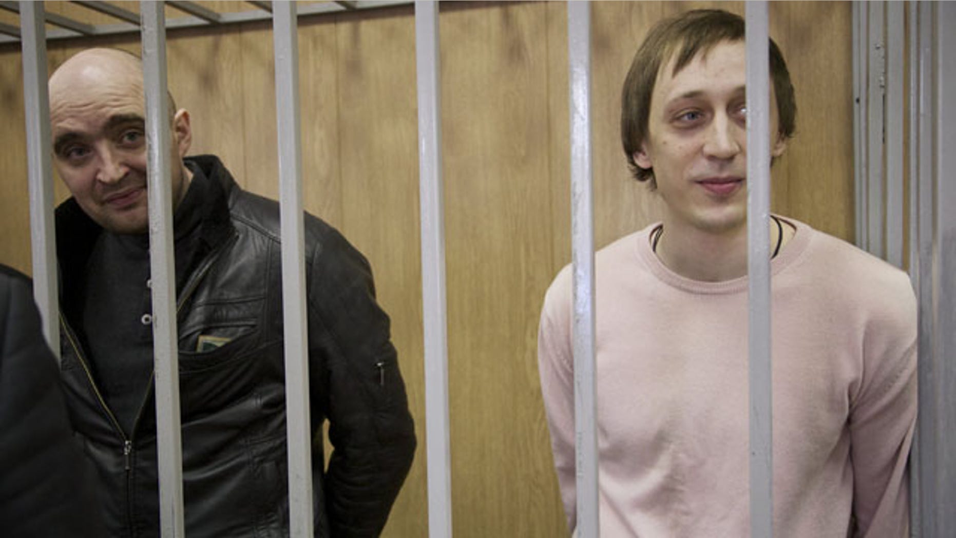 December 3, 2013: Pavel Dmitrichenko, right, a star dancer convicted of ordering a Jan. 17 acid attack on the Bolshoi Ballet's artistic director Sergei Filin, and Andrei Lipatov, stand in a cage at a court room in Moscow, Russia. (AP Photo)