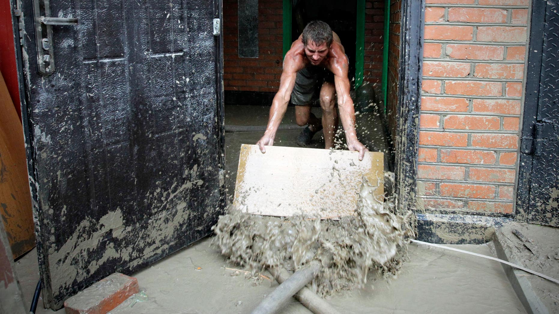 A man pushes water from his house in Krimsk, about 1,200 kilometers (750 miles) south of Moscow, Sunday July 8, 2012. Intense flooding in the Black Sea region of southern Russia killed at least 150 people after torrential rains dropped nearly a foot of water, forcing many to scramble out of their beds for refuge in trees and on roofs, officials said Saturday. (AP Photo/Sergey Ponomarev)