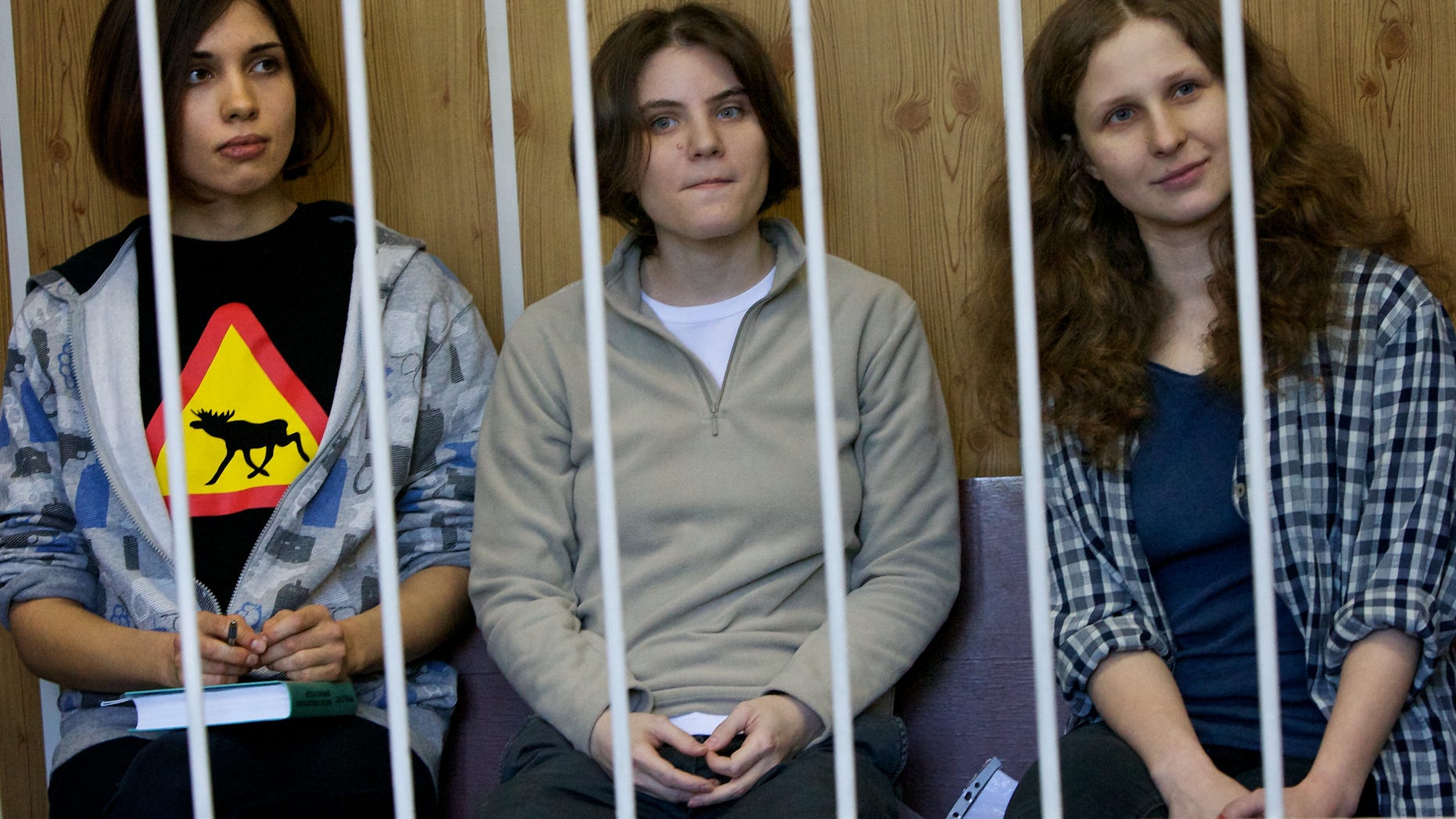 From left, Nadezhda Tolokonnikova, Maria Alekhina, Yekaterina Samutsevich members of feminist punk group Pussy Riot sit behind bars at a court room in Moscow, Russia, Monday, July 23, 2012.The trial of feminist punk rockers who chanted a "punk prayer" against President Vladimir Putin from a pulpit inside Russia's largest cathedral started in Moscow on Friday amid controversy over the prank that divided devout believers, Kremlin critics and ordinary Russians. (AP Photo/Alexander Zemlianichenko)