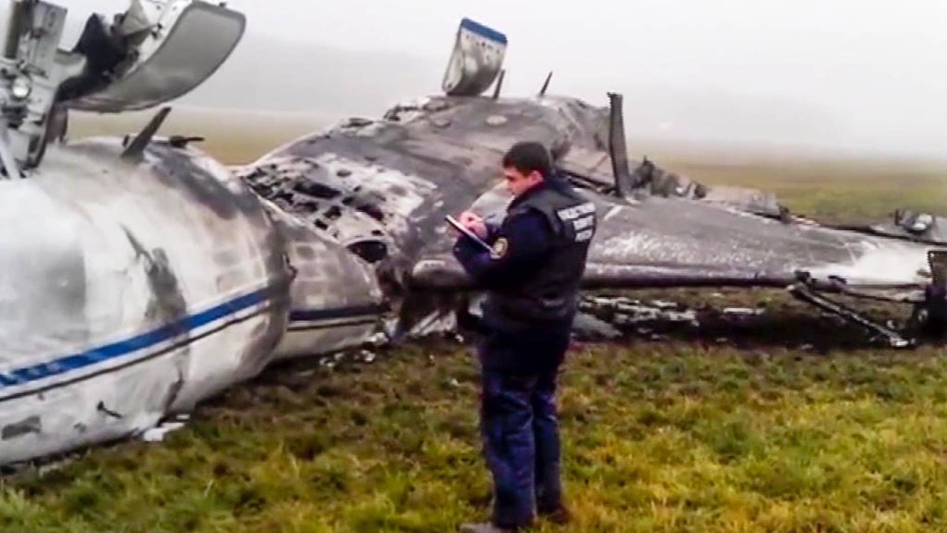 In this image made from video provided by Russian State Television Rossiya, an investigator works at the wreckage of a private jet which collided with a snowplow at Vnukovo airport in Moscow, Tuesday, Oct. 21, 2014. The head of French oil giant Total SA and three French crew members were killed at Vnukovo airport when a corporate jet, the French-made Dassault Falcon 50, collided with a snowplow, Russian investigators said Tuesday. (AP Photo) TV OUT