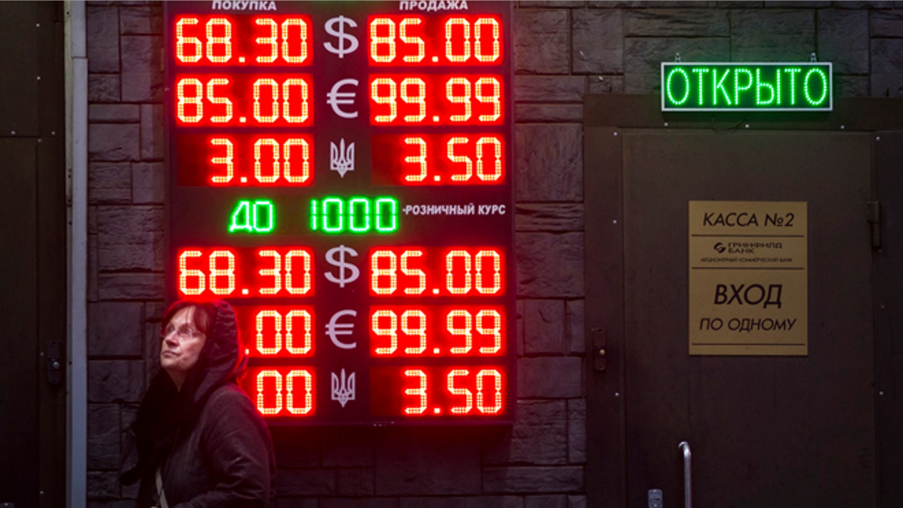 Dec. 16, 2014: People wait to exchange currency near a sign advertising currency exchange rates at an exchange office in Moscow, Russia.