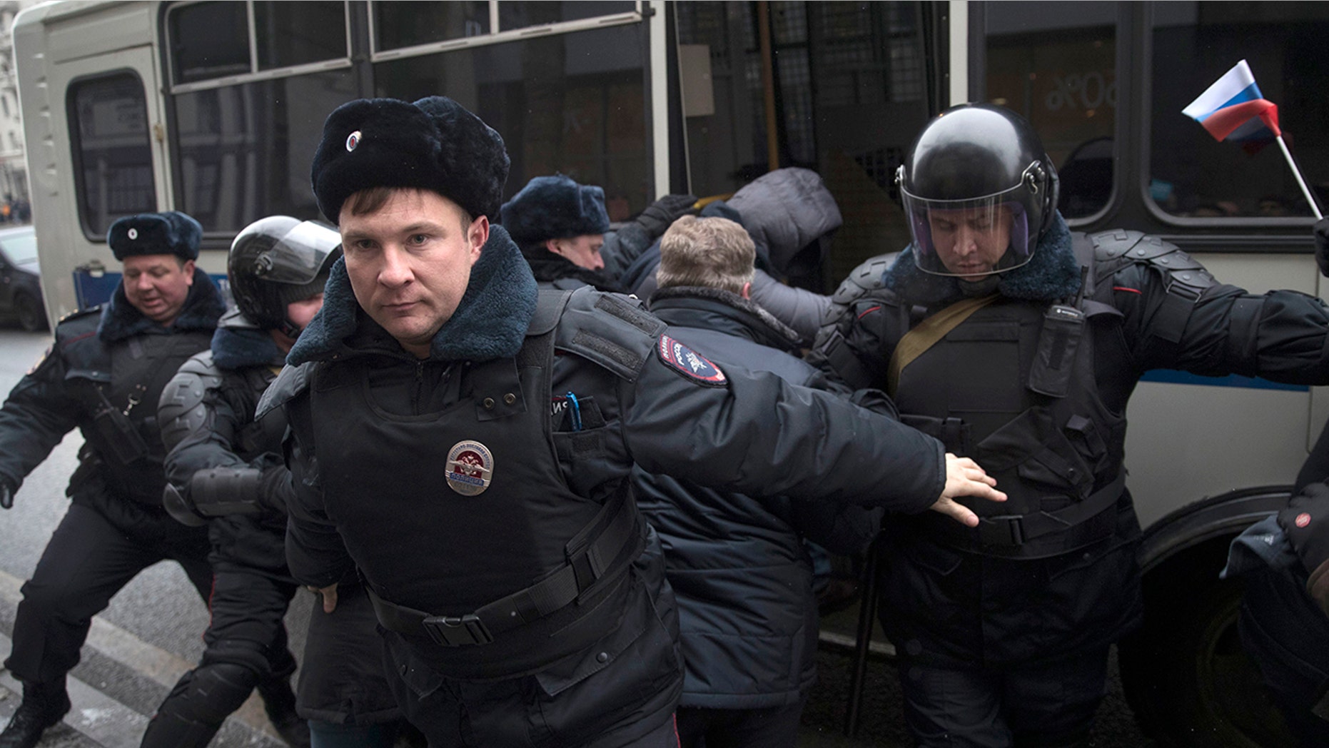 Russian opposition leader Alexei Navalny, in the background, is detained by police officers in Moscow, Russia, Sunday.