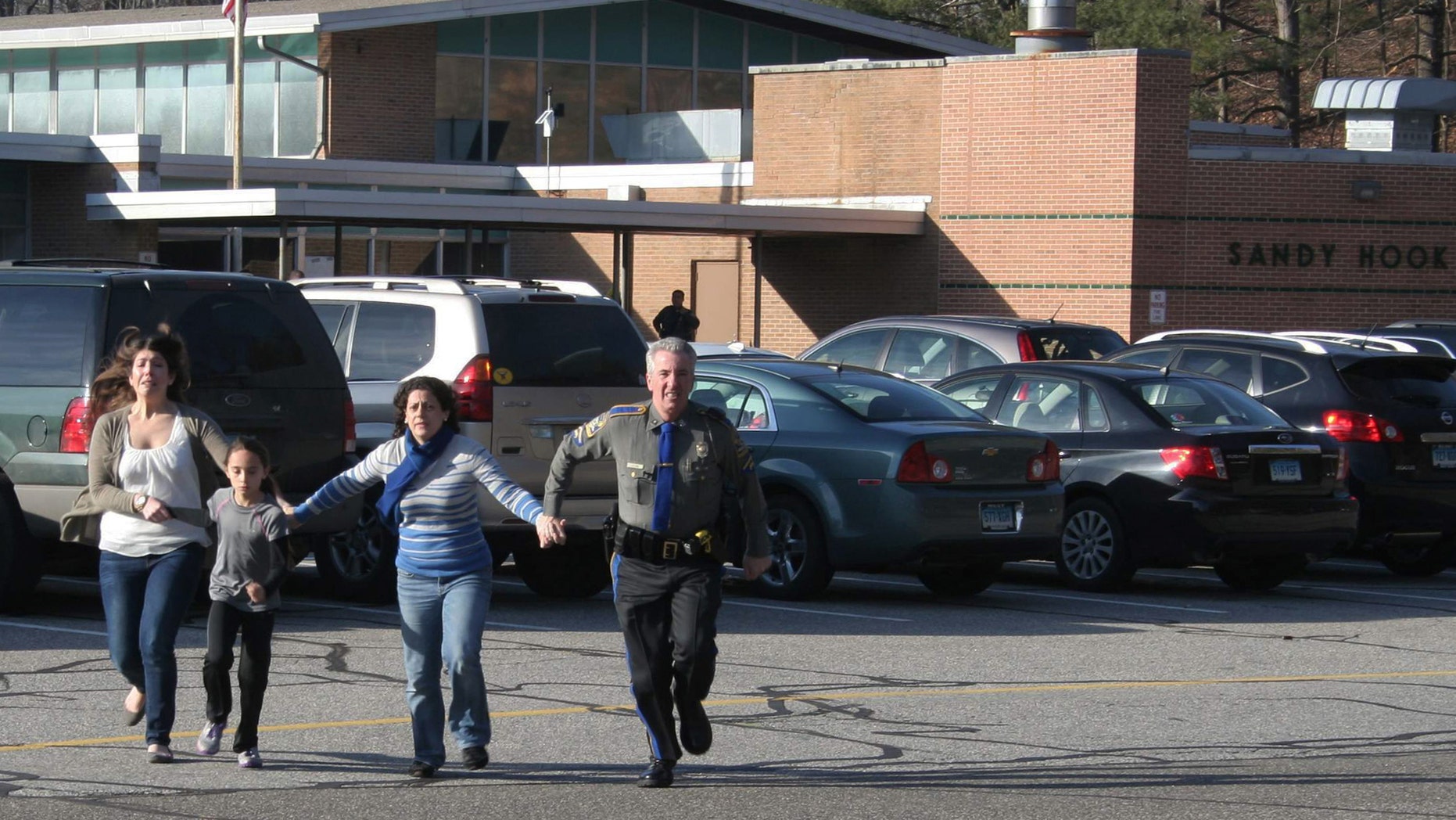 A police officer leads two women and a child from Sandy Hook Elementary School in Newtown, Conn., on Friday, Dec. 14, 2012.