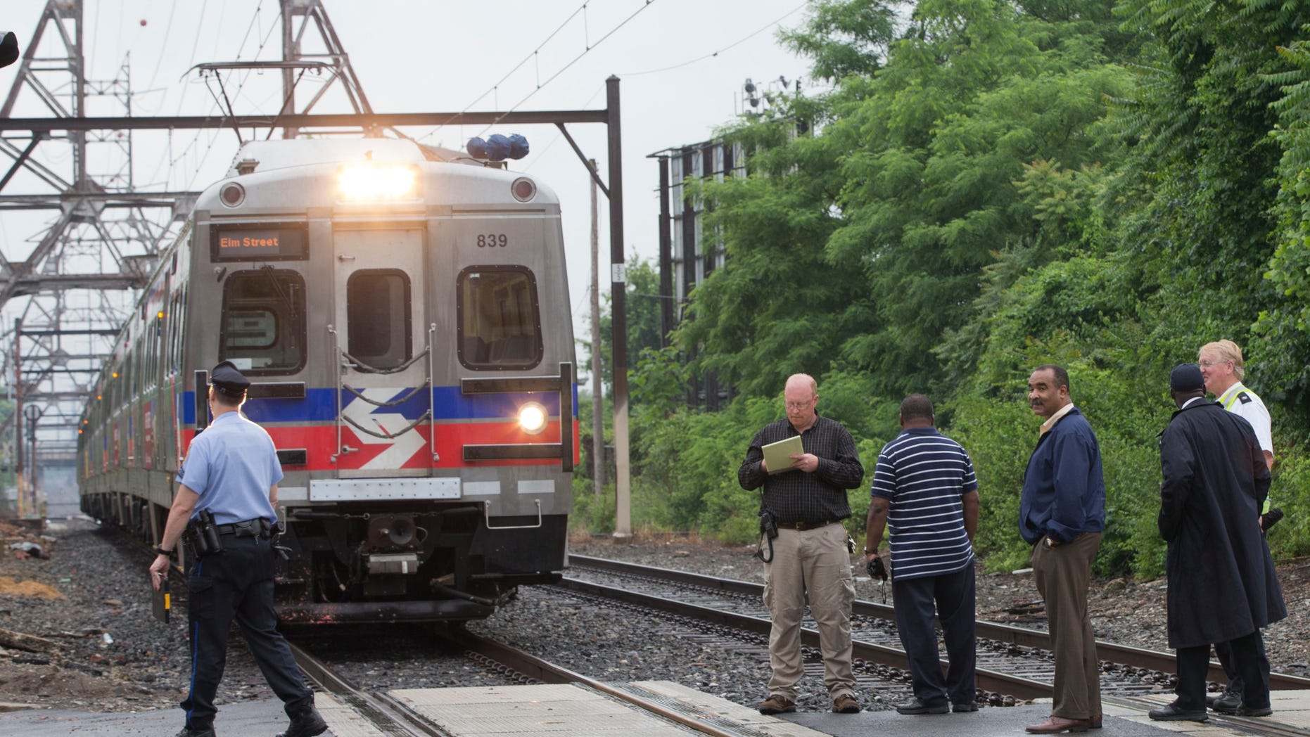 June 9, 2014: Officials stand near an idle Southeastern Pennsylvania Transportation Authority train.