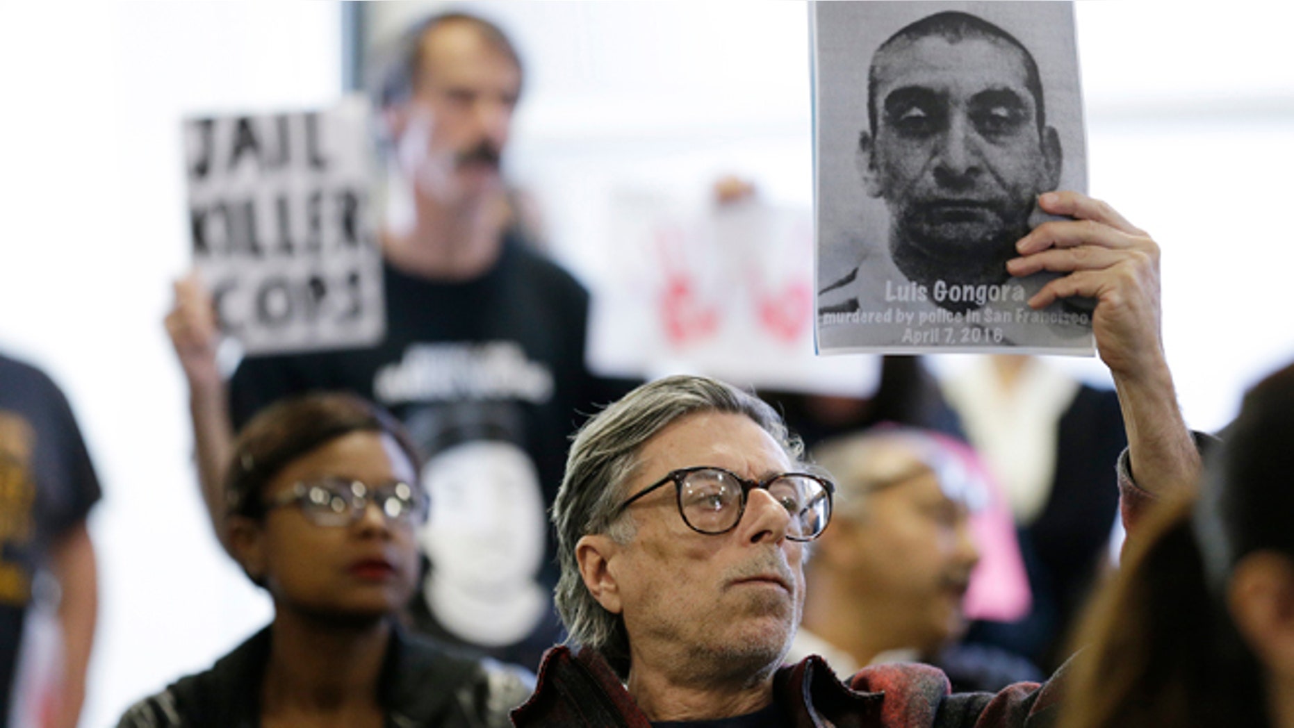 A man holds up a picture of Luis Gongora during a town hall meeting Wednesday, April 13, 2016, in San Francisco.