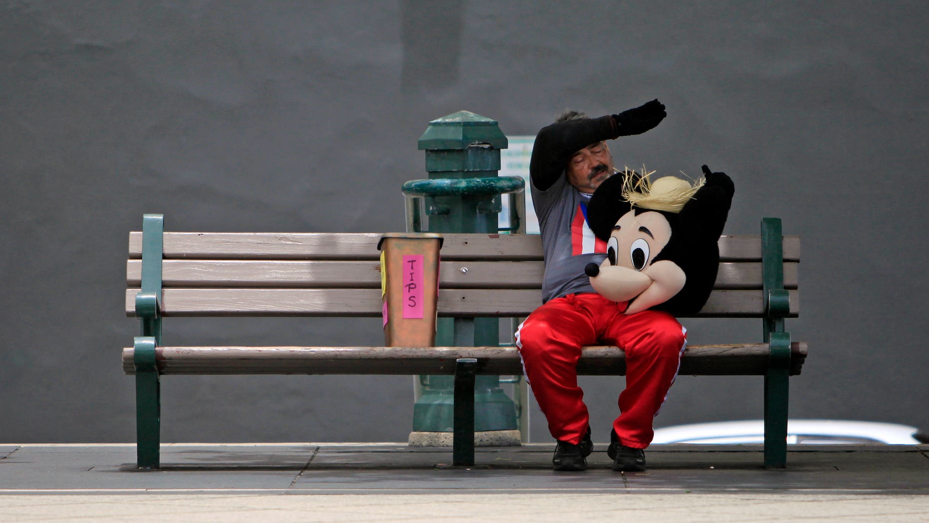 A street performer dressed as Mickey Mouse rests on a bench in Old San Juan, Puerto Rico, on July 1, 2015.