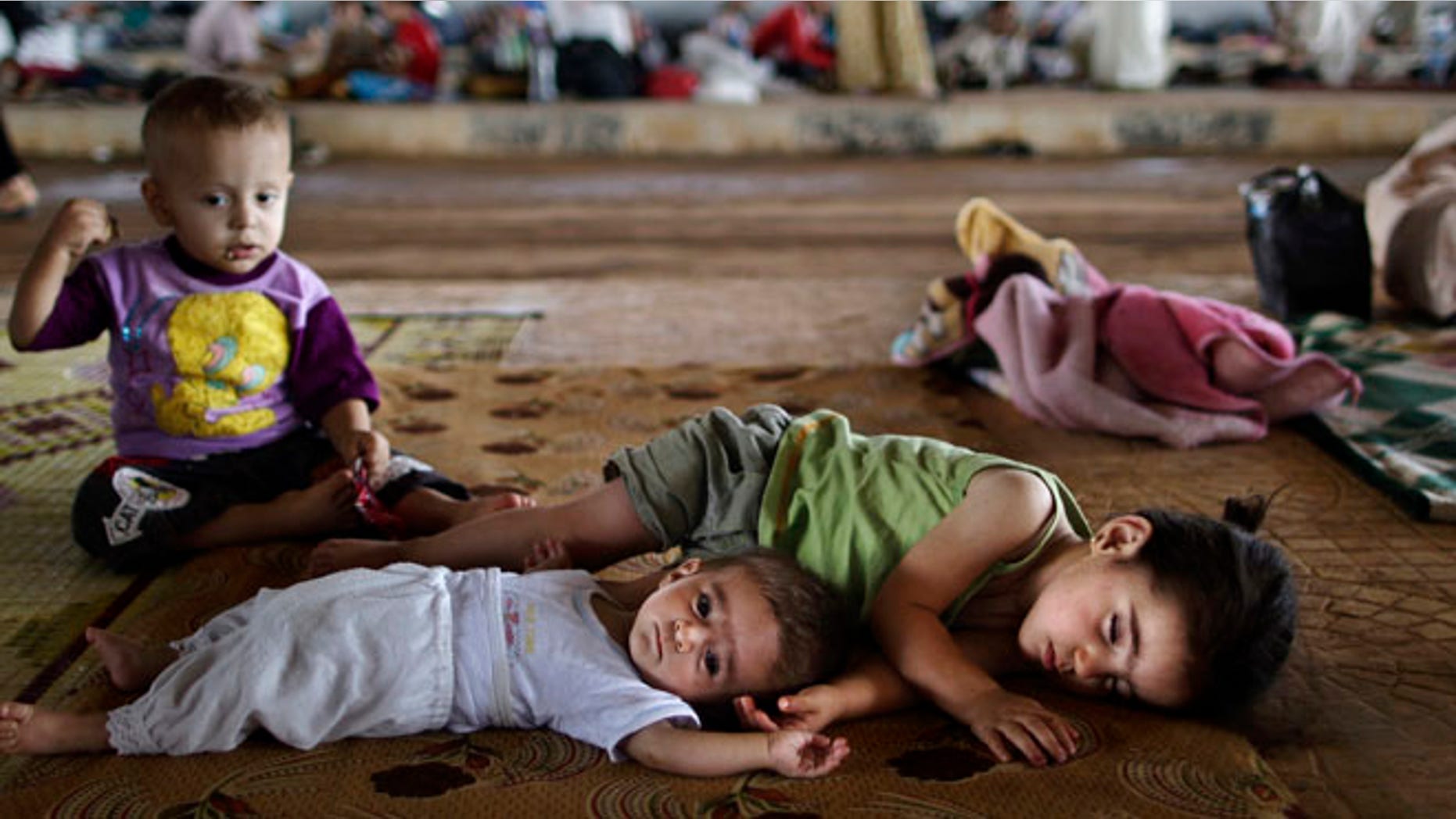 Aug. 26, 2012: Syrian children who fled their home lie on the ground while they and others take refuge at the Bab Al-Salameh border.