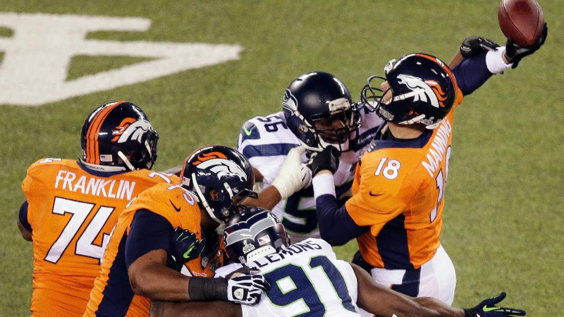 FILE - In this Feb. 2, 2014, file photo, Denver Broncos' Peyton Manning is hit by Seattle Seahawks' Cliff Avril (56) during the first half of the NFL Super Bowl XLVIII football game in East Rutherford, N.J. One of the hallmarks of the Seahawks’ Super Bowl run was the ability to wreak havoc on quarterbacks but this season Seattle’s pass rush is not close to matching its effectiveness from last year. (AP Photo/Charlie Riedel, File)