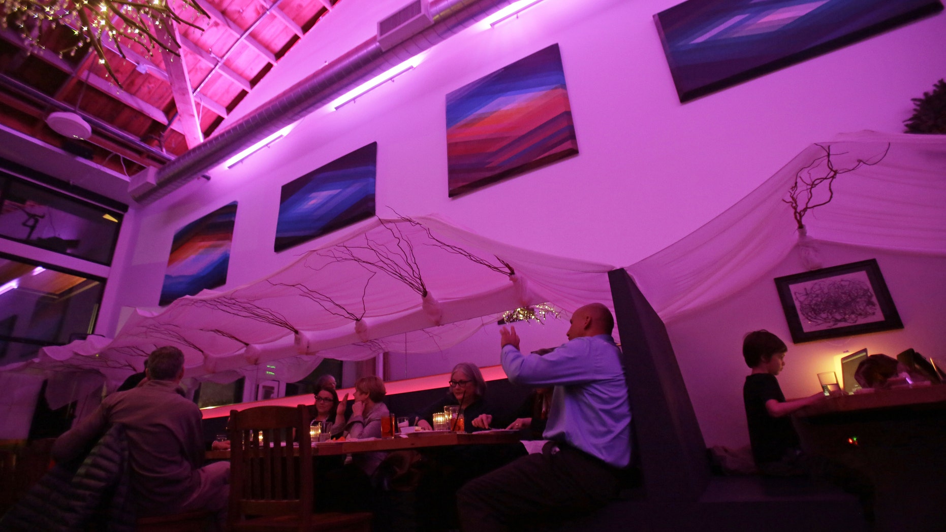 Lightbar patrons are bathed in a purple glow from special lights in Portland, Ore., Thursday, Dec. 19, 2013. (AP Photo/Don Ryan)