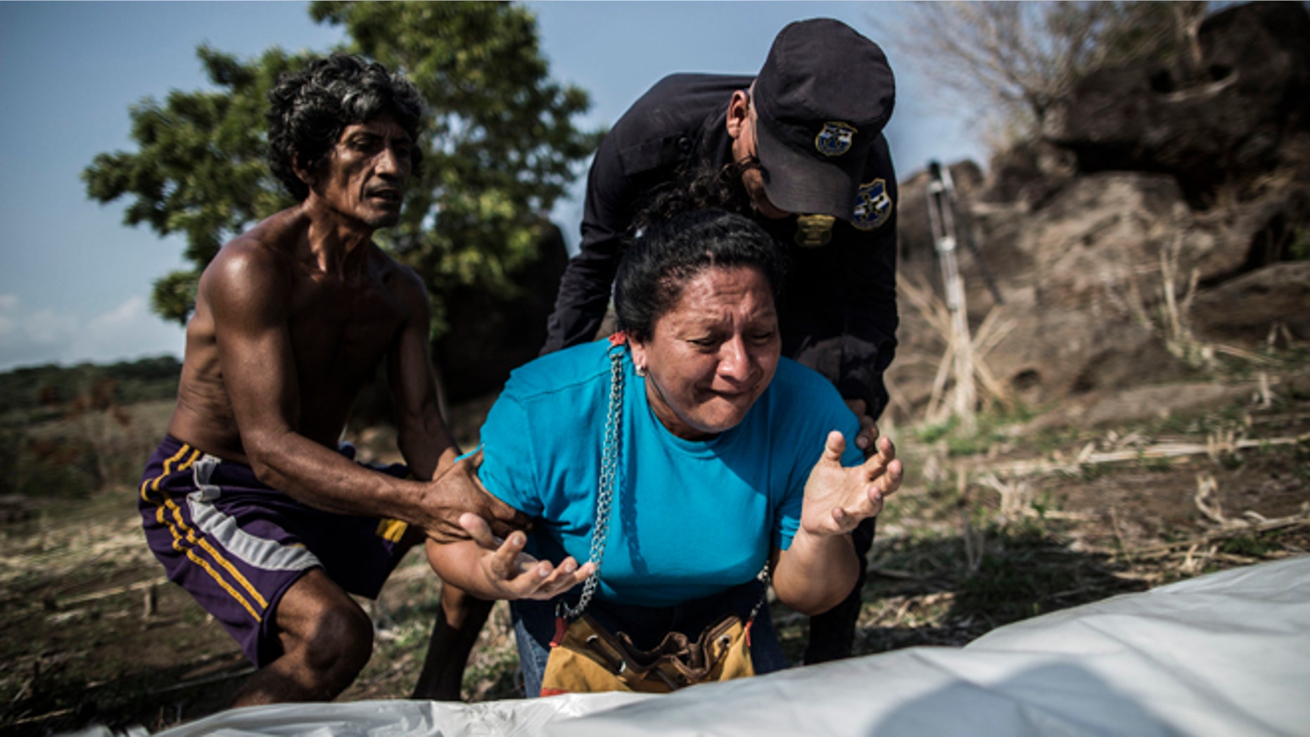 FILE - In this May 28, 2015, file photo, the sister of Alberto Hernández Escalante mourns over the body of her brother, found in a clandestine grave, in a rural area near Caserio el Chumpe, El Salvador. (AP Photo/Manu Brabo, File)