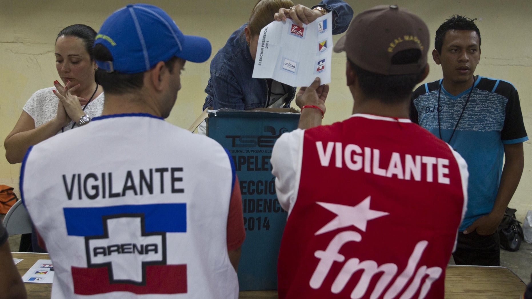 An election officer shows a ballot in front volounteers from the ruling the Farabundo Marti National Liberation Front, (FMLN) and Nationalist Republican Alliance, or ARENA, during during the vote count at a polling station in San Salvador, El Salvador, Sunday, Feb. 2, 2014. Presidential elections in two Central American countries are both referendums on political stagnation, with voters in Costa Rica deciding whether to oust the long-ruling party, and voters in El Salvador deciding whether to bring it back to power. (AP Photo/Esteban Felix)